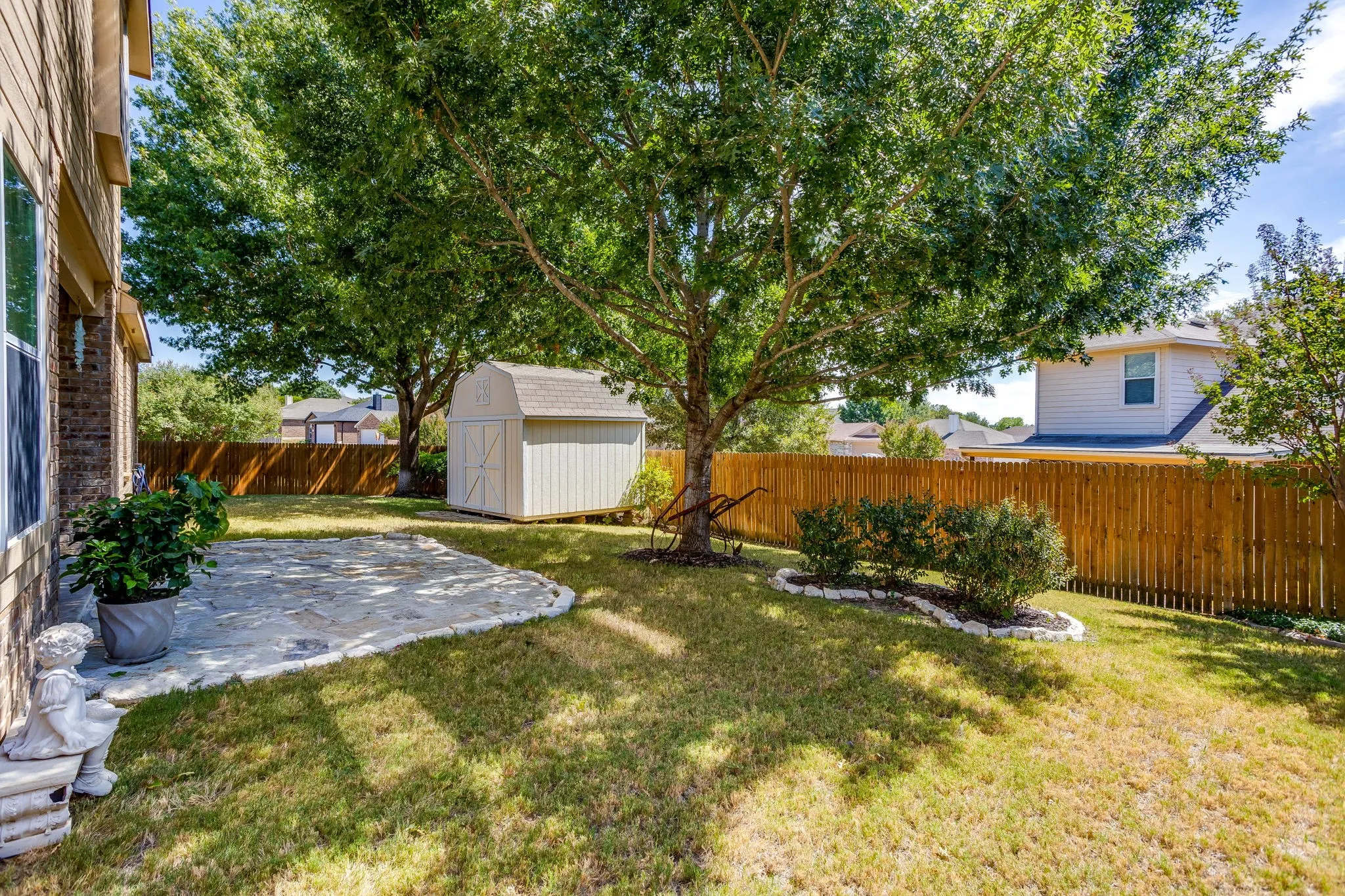 Beautiful backyard with flagstone patio, Large mature trees and storage building.