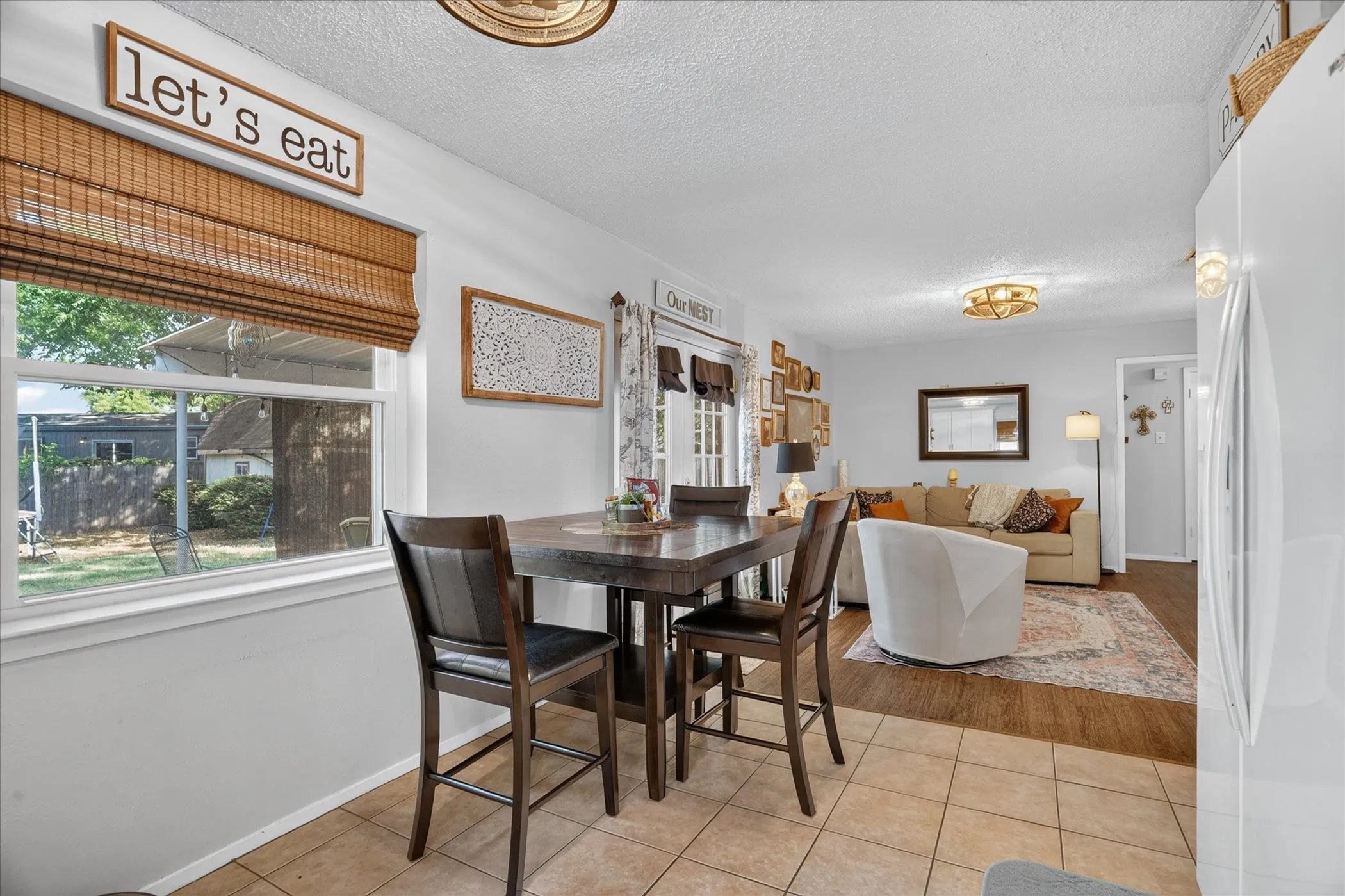 Tiled flooring in dining area, wood-finish flooring in living area, and a window with a woven shade