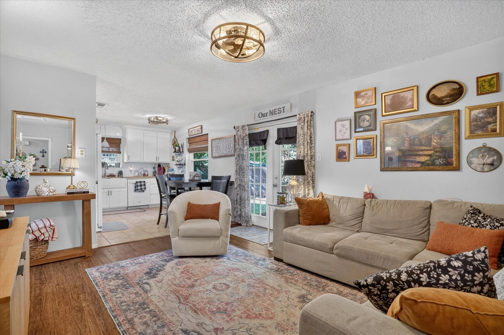 Recessed lighting, wood-finish flooring, white kitchen cabinetry, and a glass-paneled exterior door