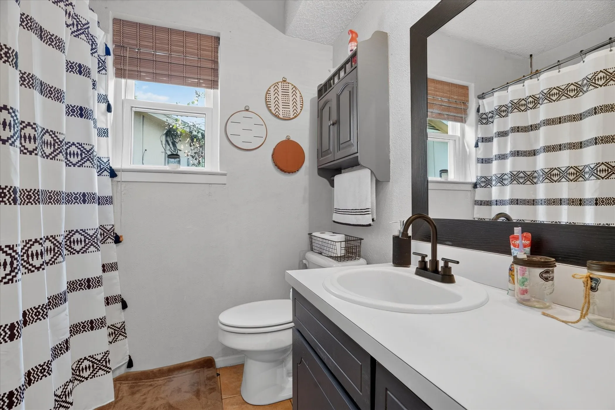 Bathroom featuring a white vanity with an integrated sink, dark bronze-finish fixtures, a framed mirror, and a wall-mounted storage cabinet