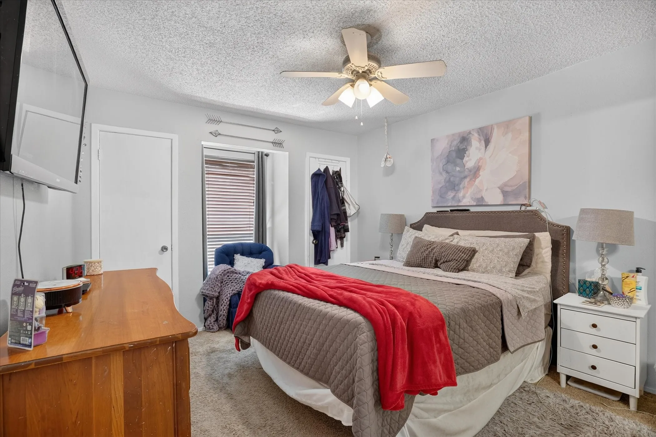 Ceiling fan with integrated lighting, textured ceiling, window with blinds, light gray wall paint, and carpet flooring