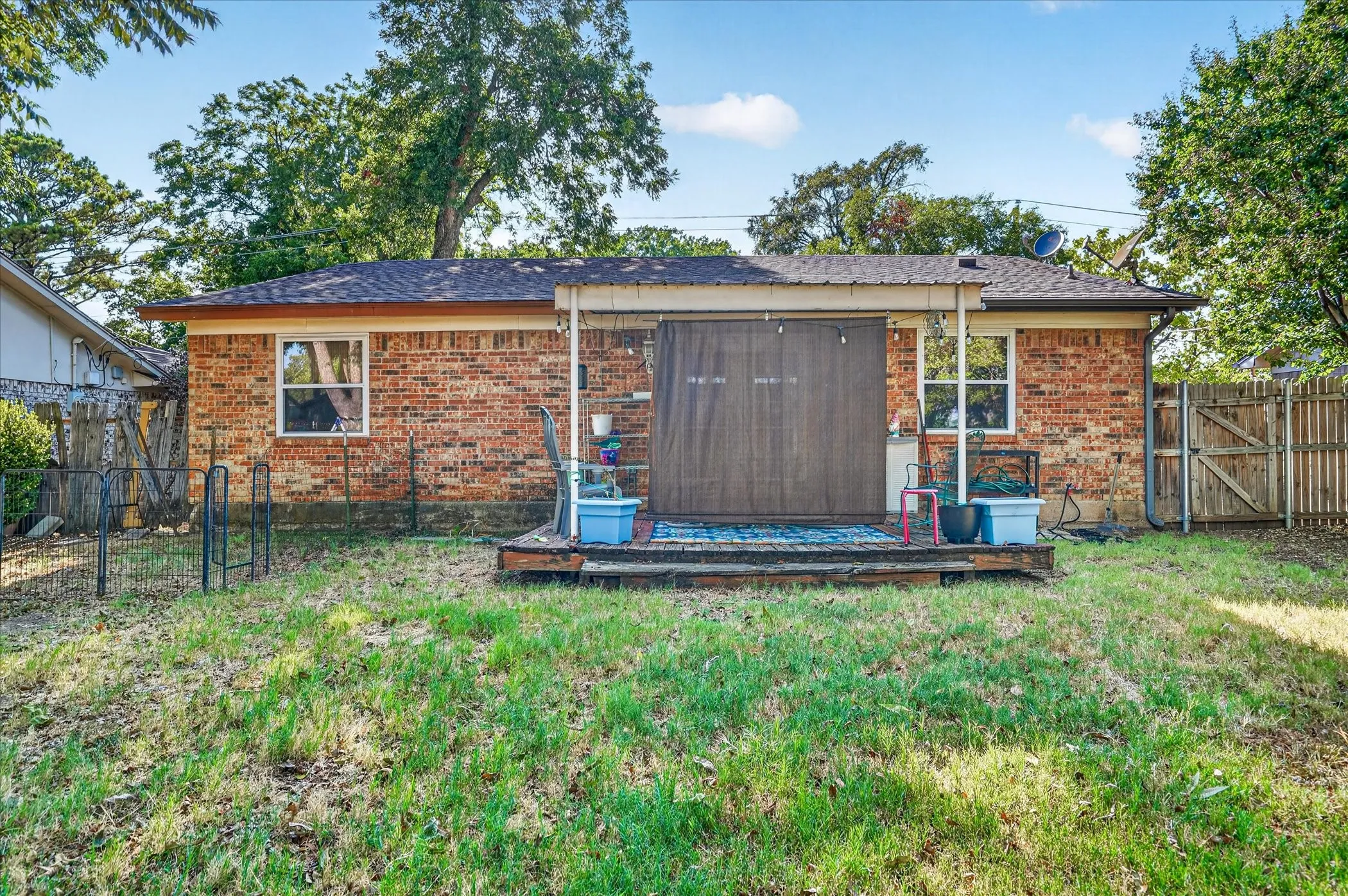 Brick exterior with multiple windows, covered patio, and wood fencing