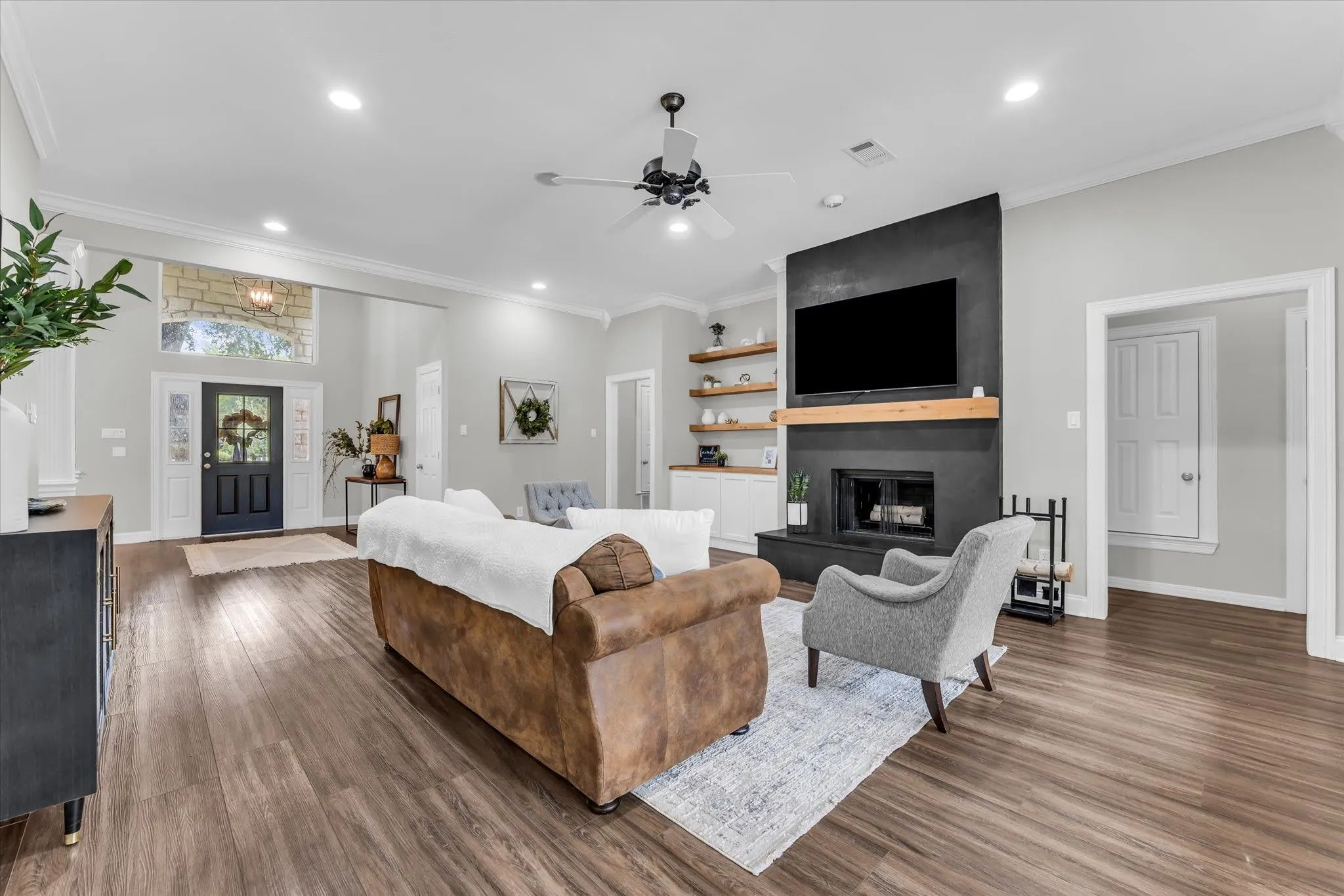 Spacious living area featuring wood-finish flooring, a contemporary fireplace with a wood mantle, and built-in shelving