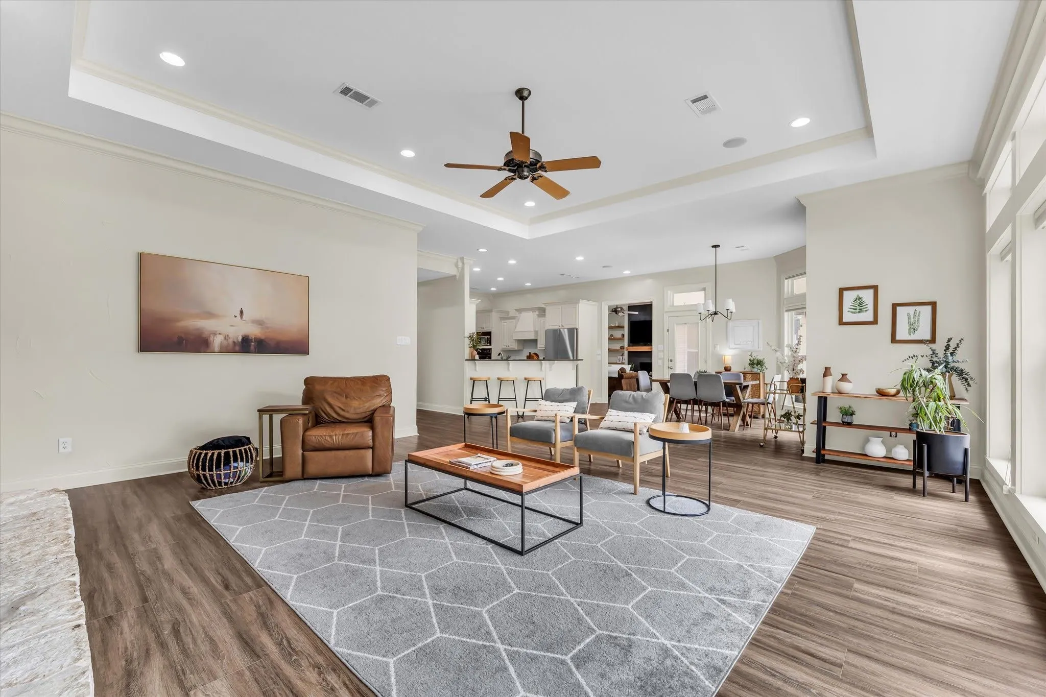 Expansive living area with wood-finish flooring, a tray ceiling, recessed lighting, and large windows
