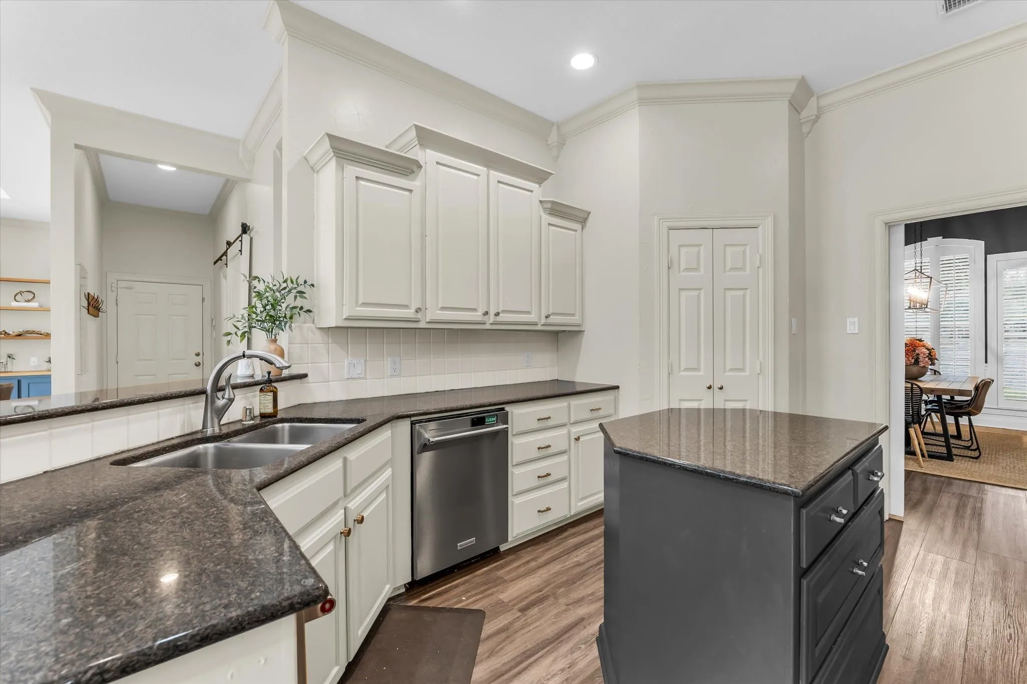 Kitchen featuring dark stone countertops, wood-finish flooring, white cabinetry, stainless steel appliances, and a central island with storage