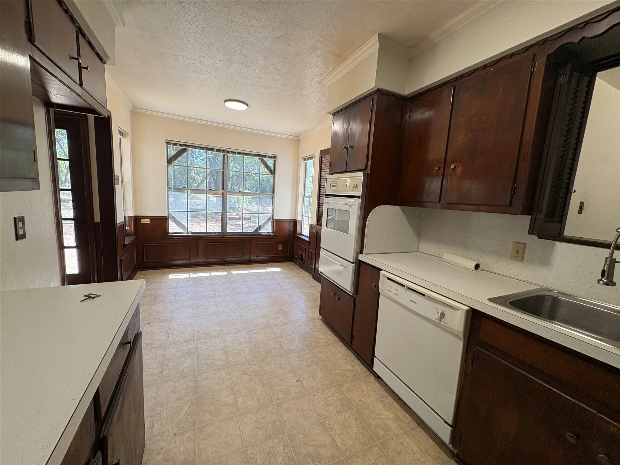 Kitchen featuring wood cabinetry, white countertops, a double wall oven, and an integrated dishwasher