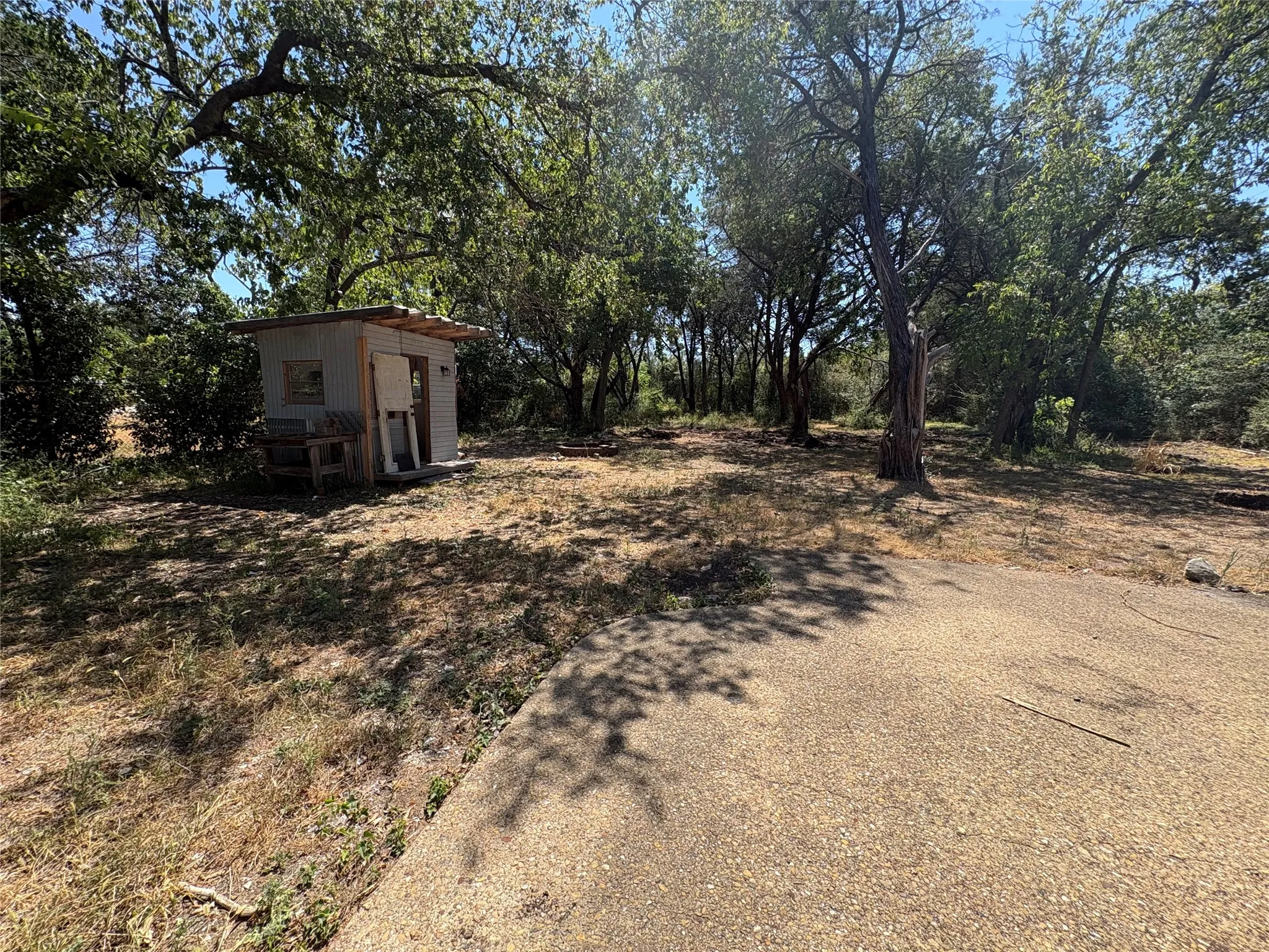 Wooded lot featuring mature trees and a gravel pathway