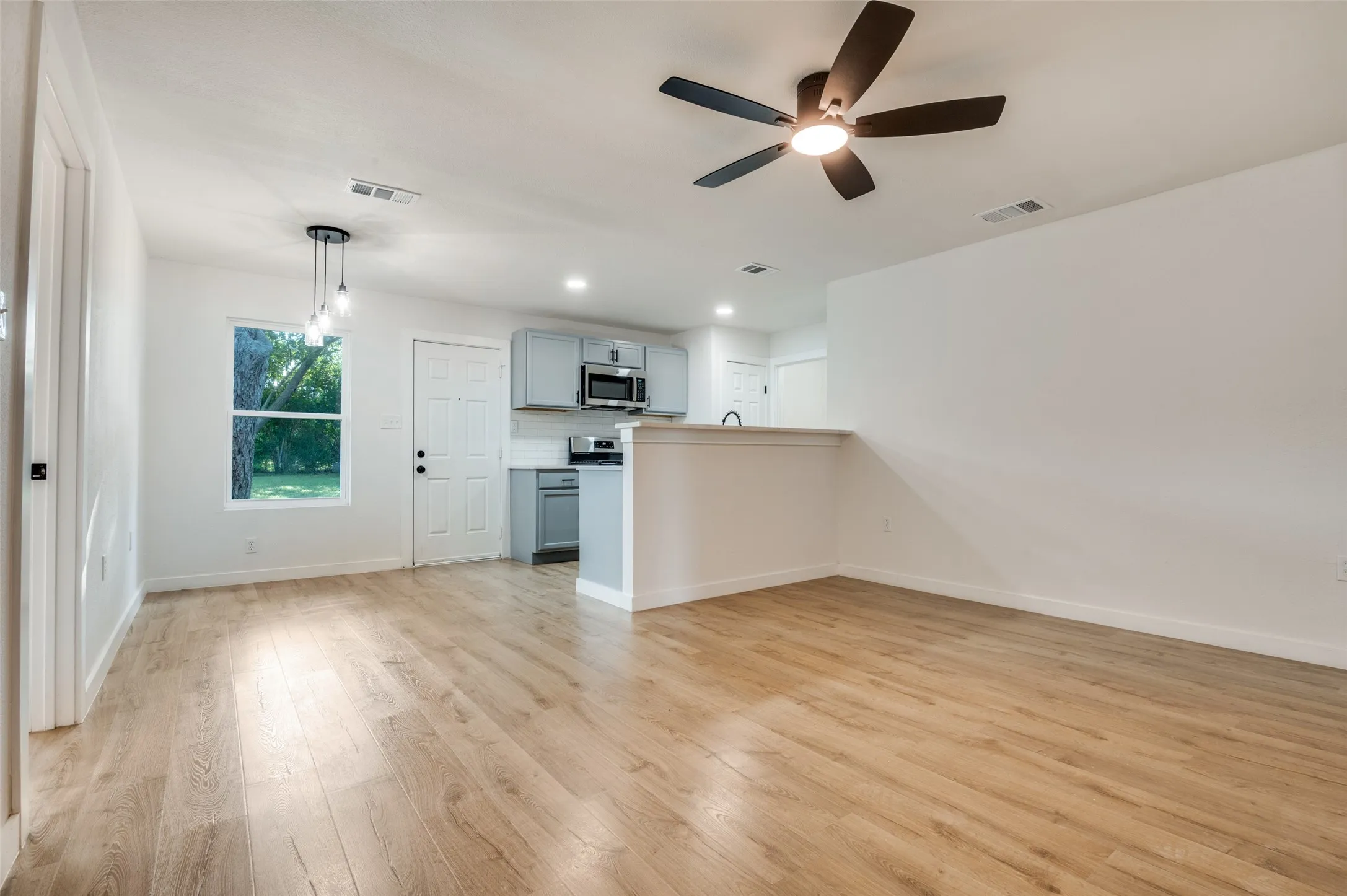 Unfurnished living room featuring light wood-type flooring, a ceiling fan, and recessed lighting