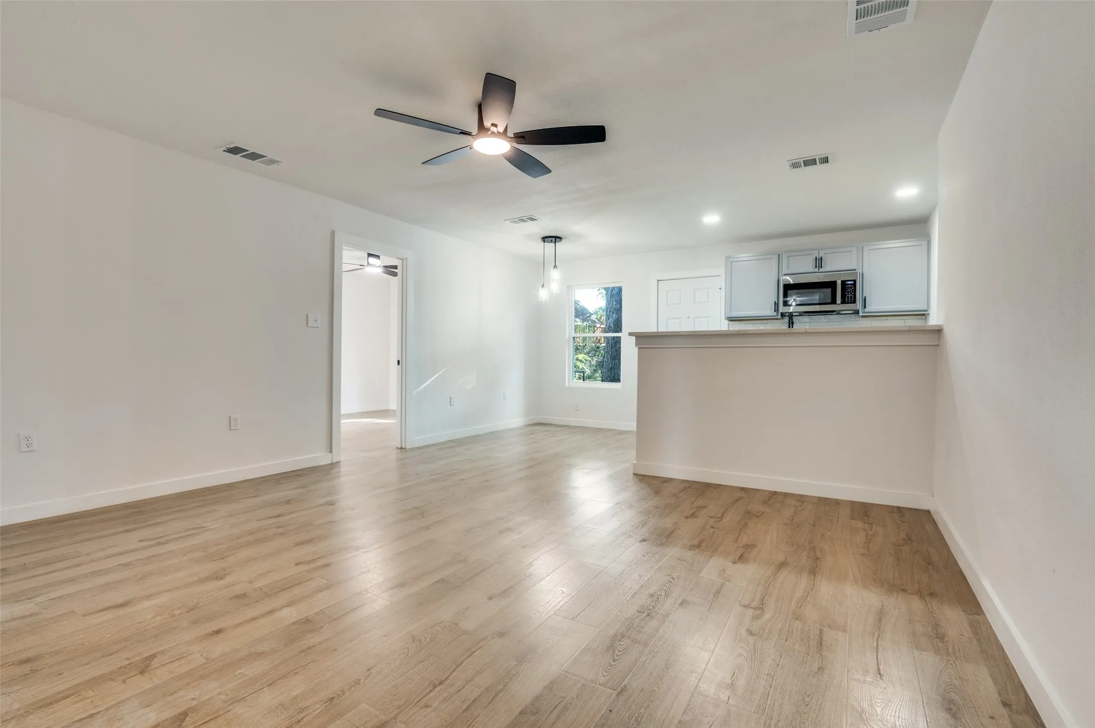 Unfurnished living room with light wood-type flooring, ceiling fan, and recessed lighting