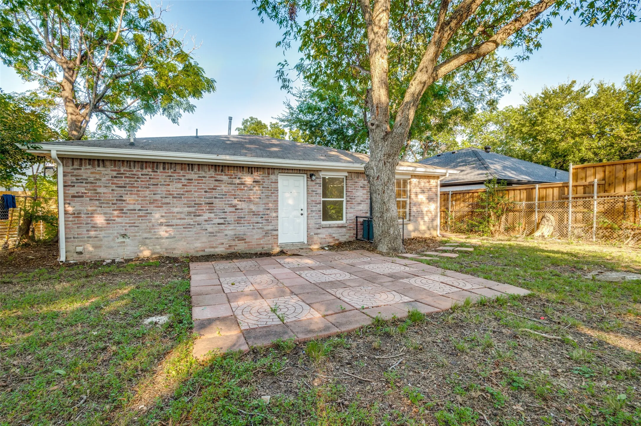 Rear view of property with a patio, a fenced backyard, brick siding, and a shingled roof