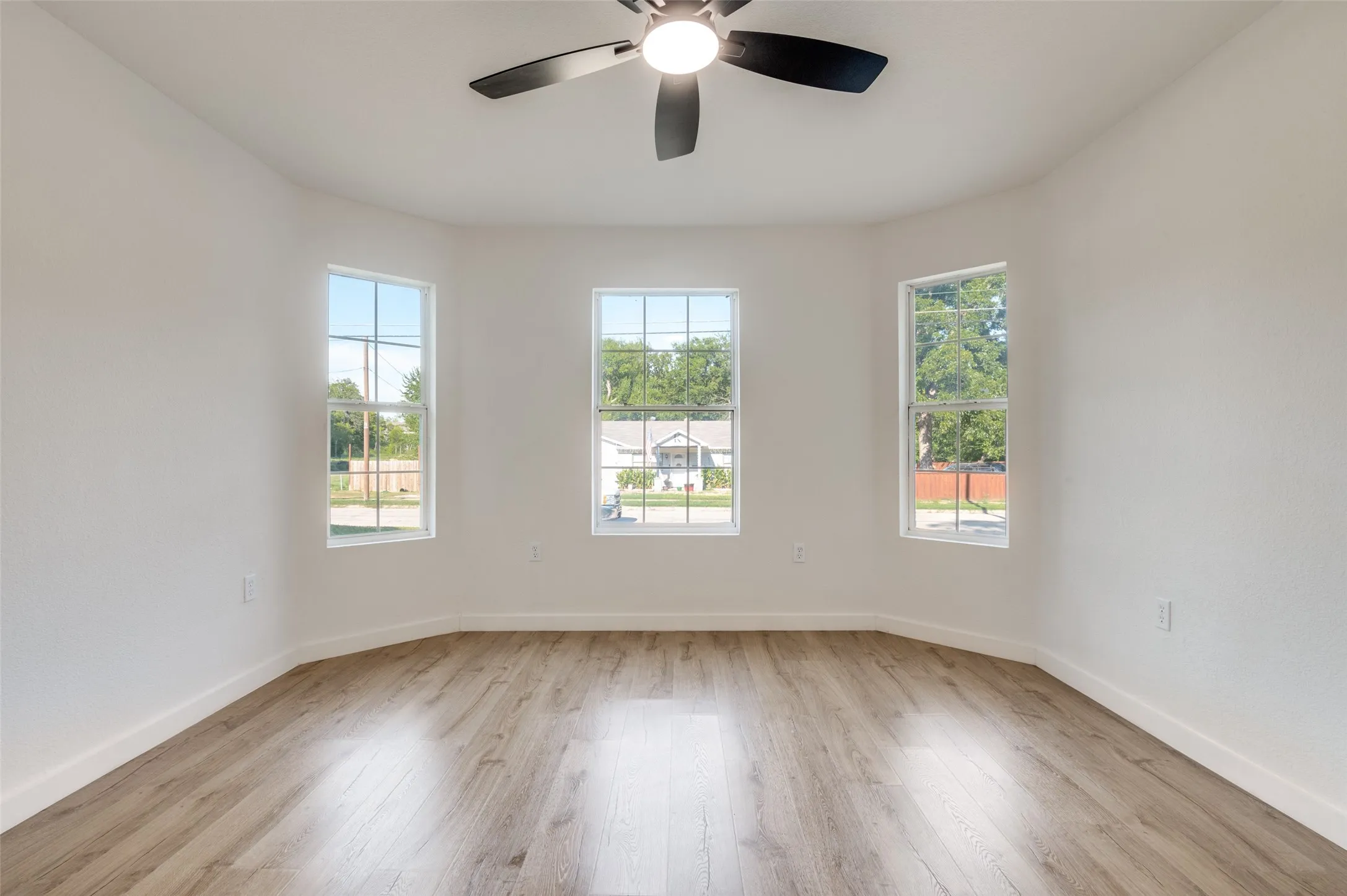 Unfurnished room with light wood-style floors, healthy amount of natural light, and ceiling fan