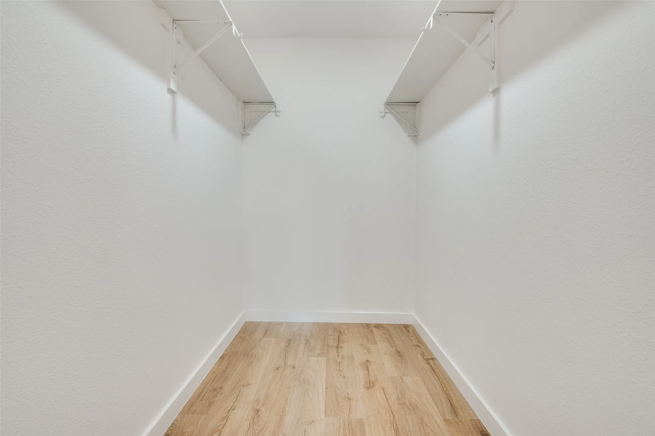 Walk in closet with light wood-style floors