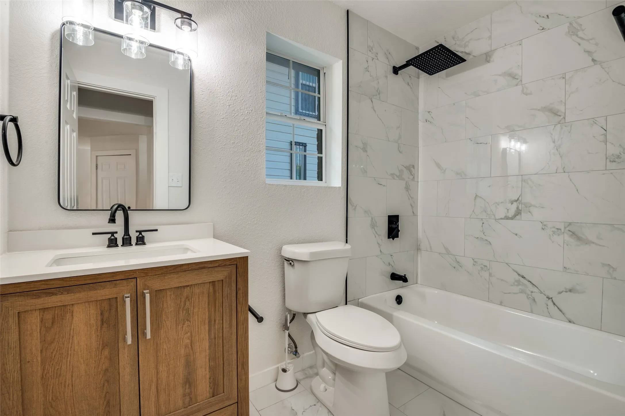 Full bathroom featuring a textured wall, shower / bath combination, and vanity