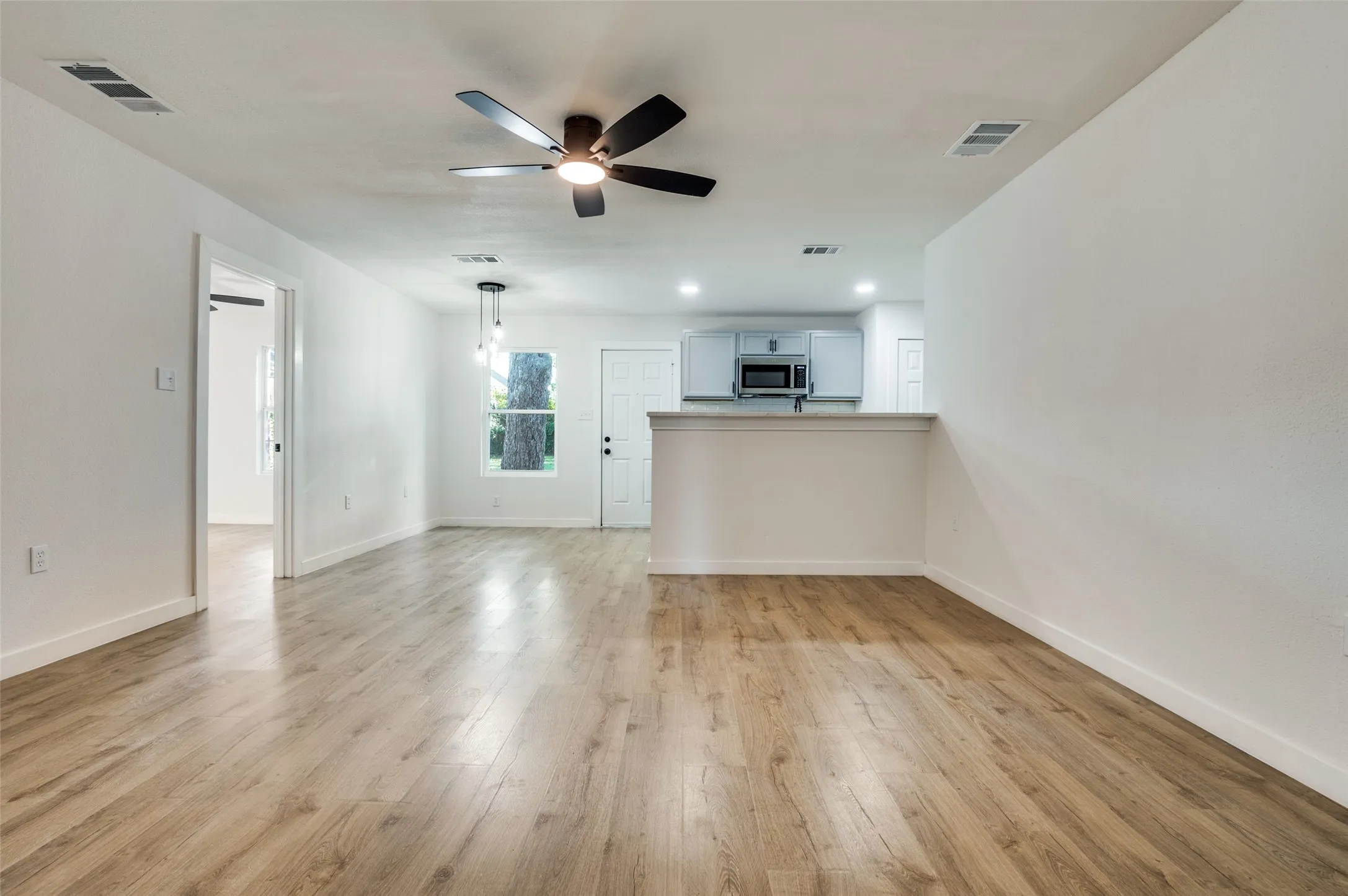 Unfurnished living room with light wood finished floors, a ceiling fan, and recessed lighting
