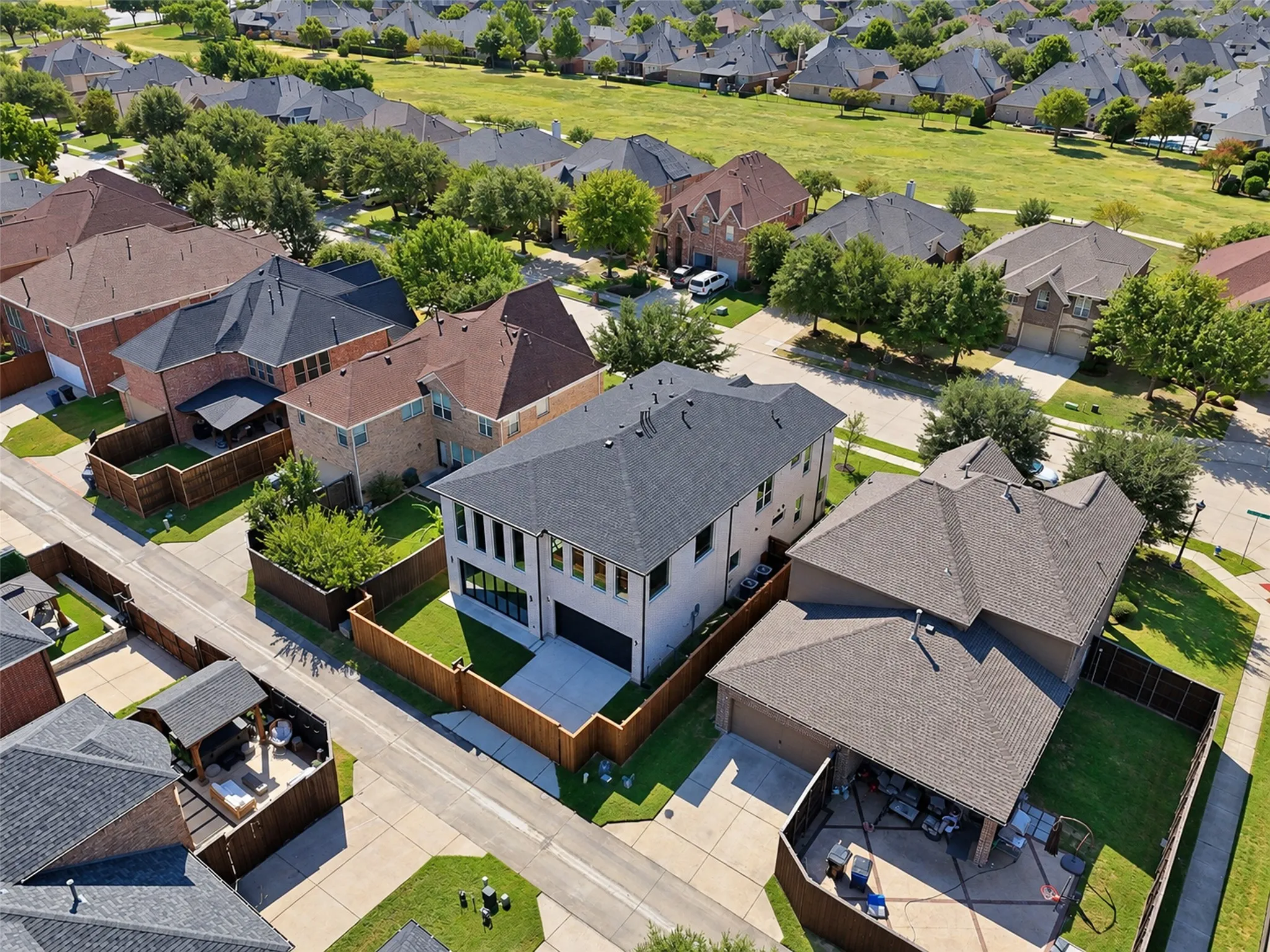 Modern residence featuring a dark gray roof, light-colored exterior, and multiple large windows