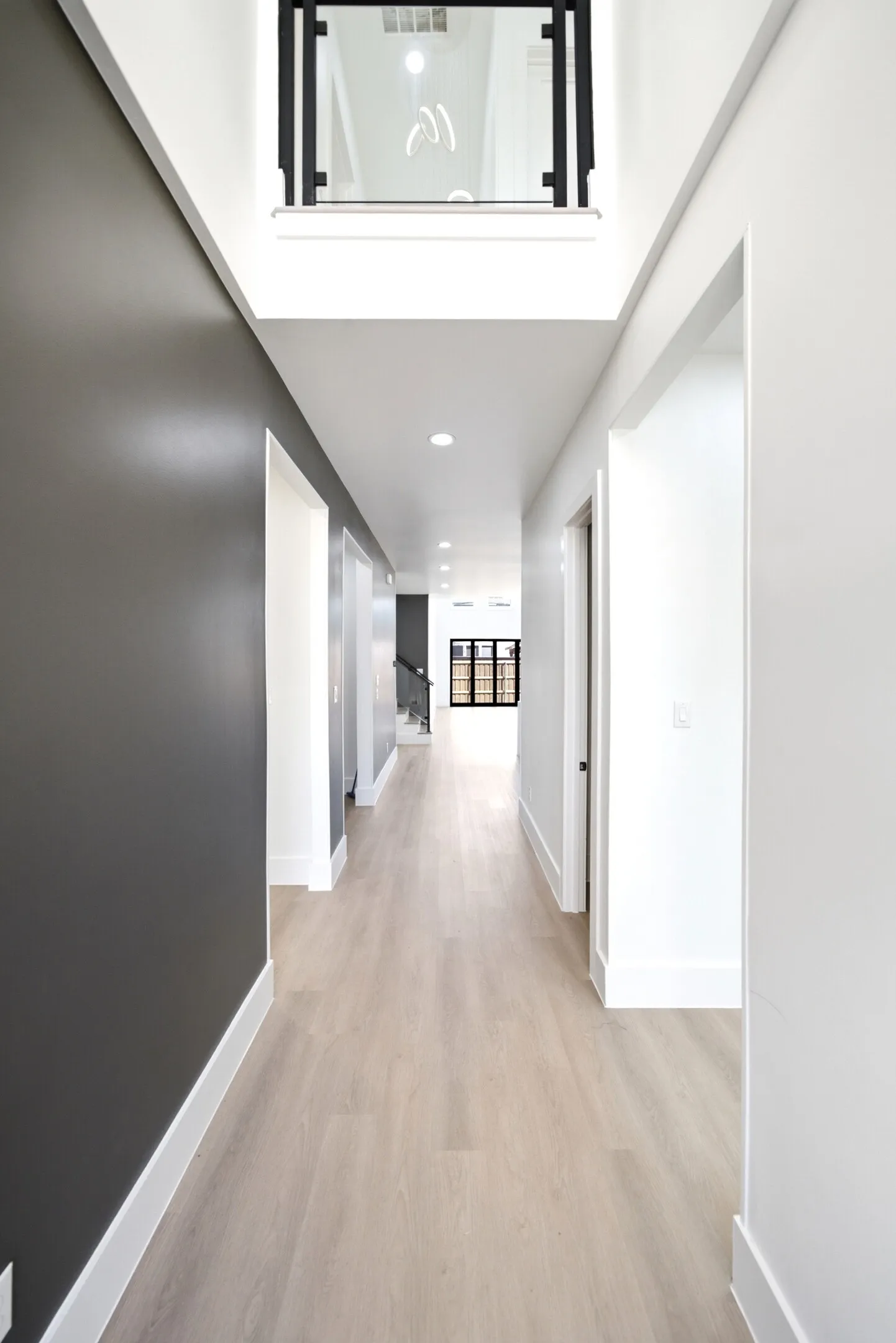 Wood-finish flooring throughout, recessed ceiling lights, and an upper-level interior window with black framing
