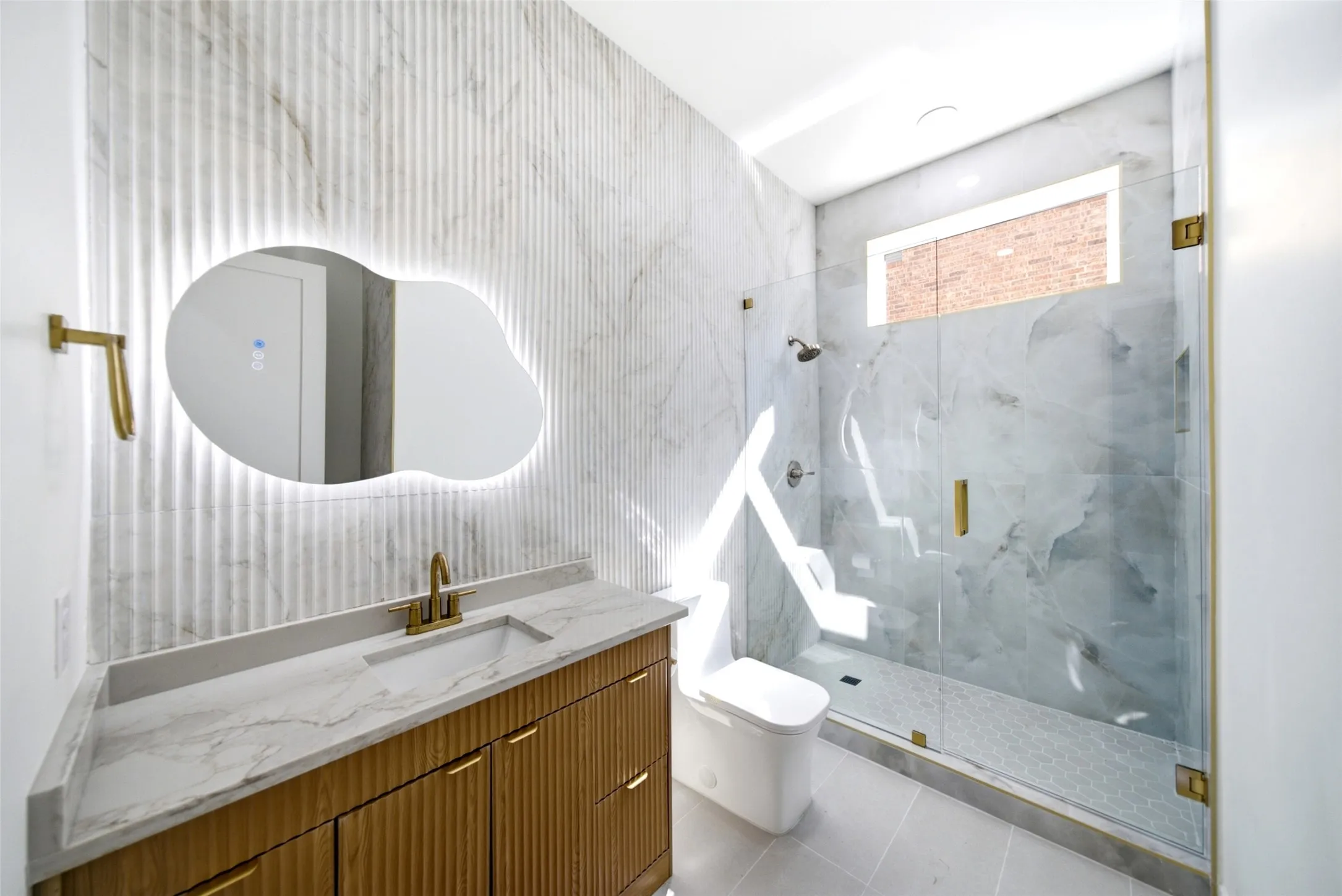 Modern vanity with a light-toned countertop, integrated sink, and gold-finish faucet