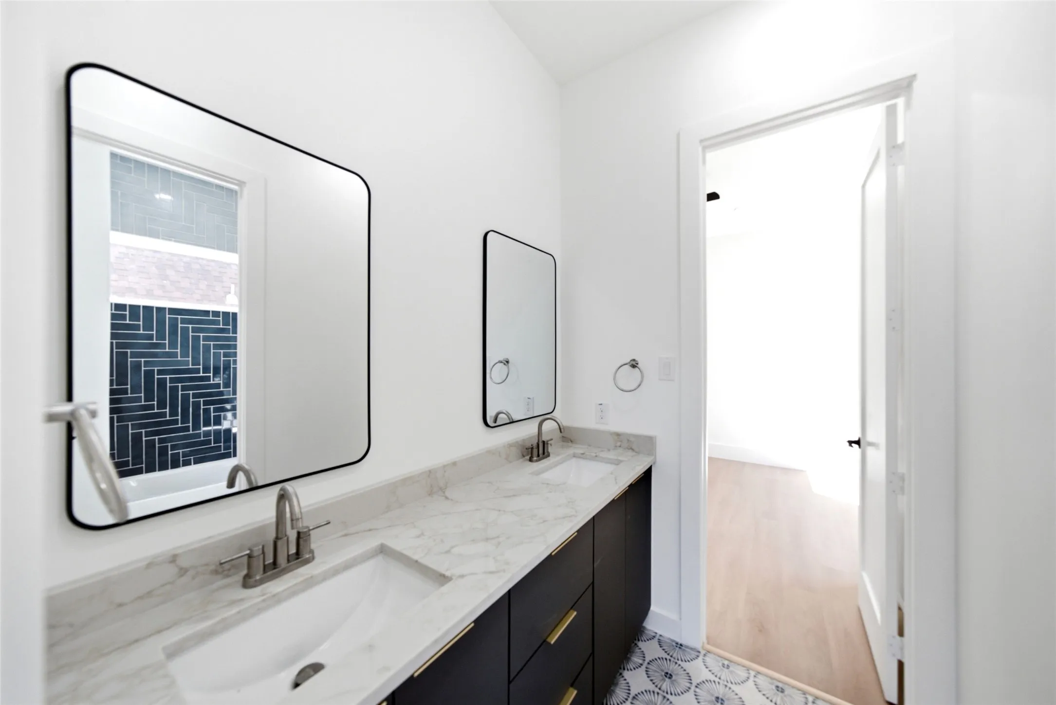 Dual vanity featuring a light-toned countertop, under-mount sinks, and matte black cabinetry with gold-toned hardware