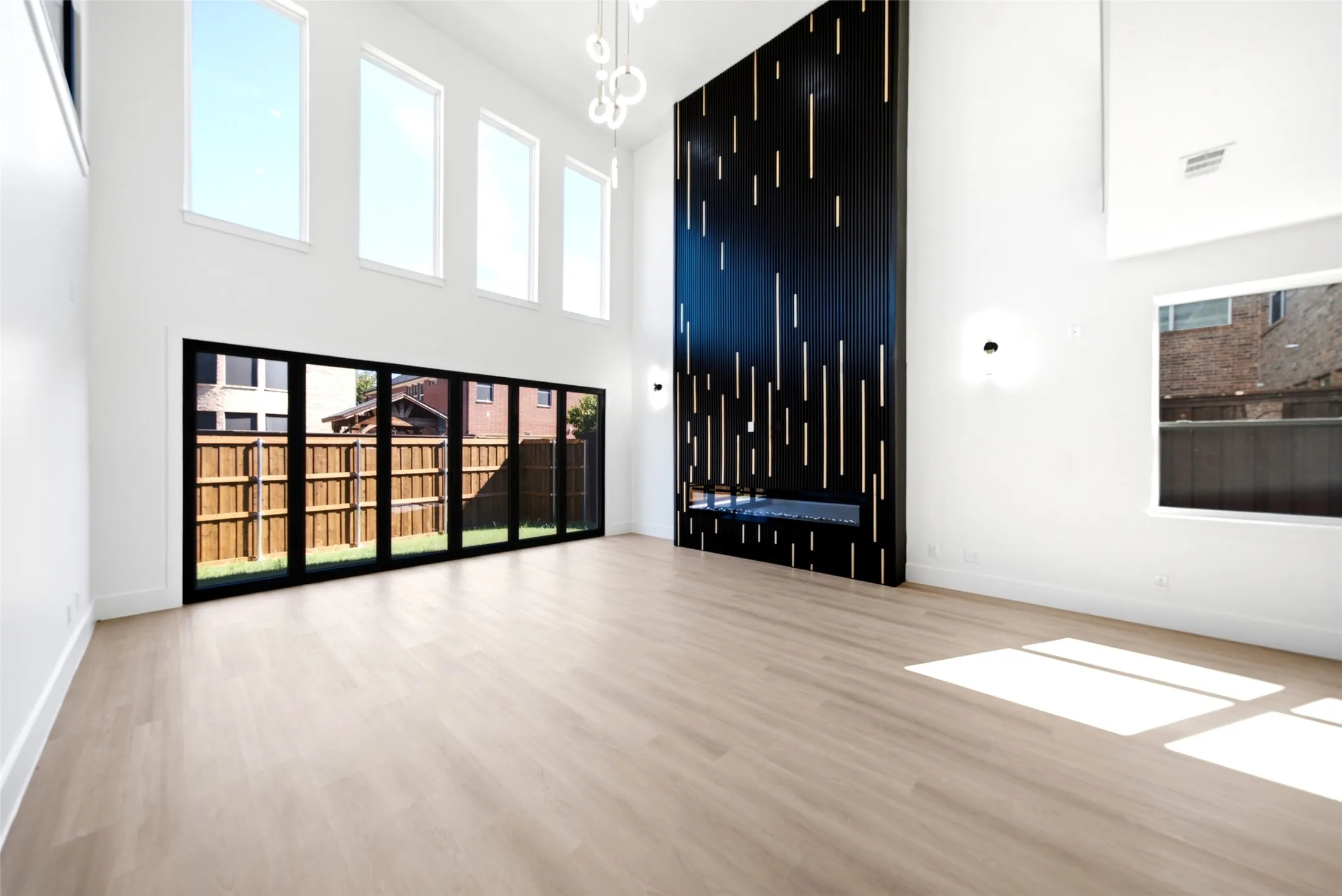 Vaulted ceiling, wood-finish flooring, extensive bi-fold glass doors, linear fireplace, and high transom windows