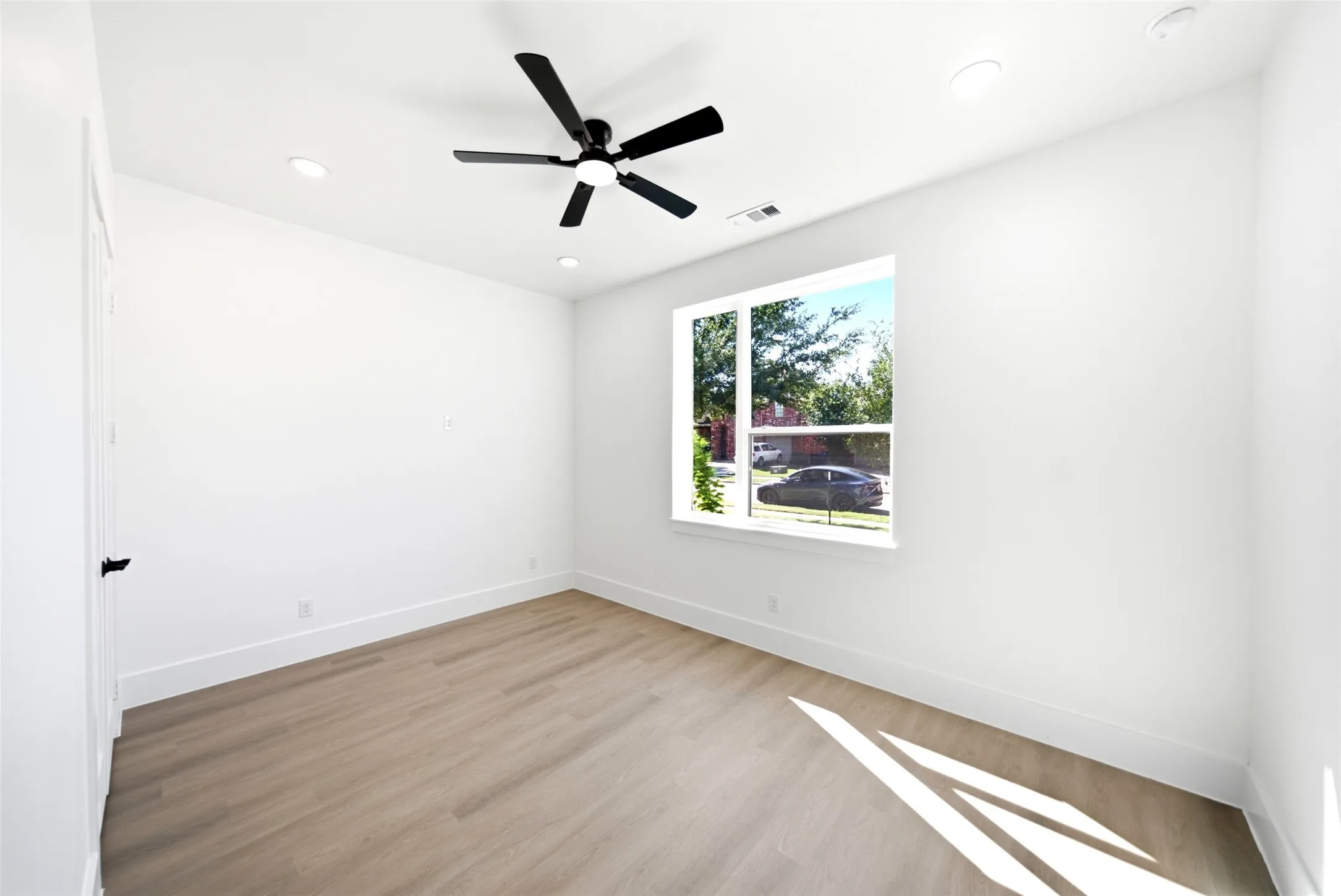 Recessed lighting, wood-finish flooring, white walls, ceiling fan, and large window