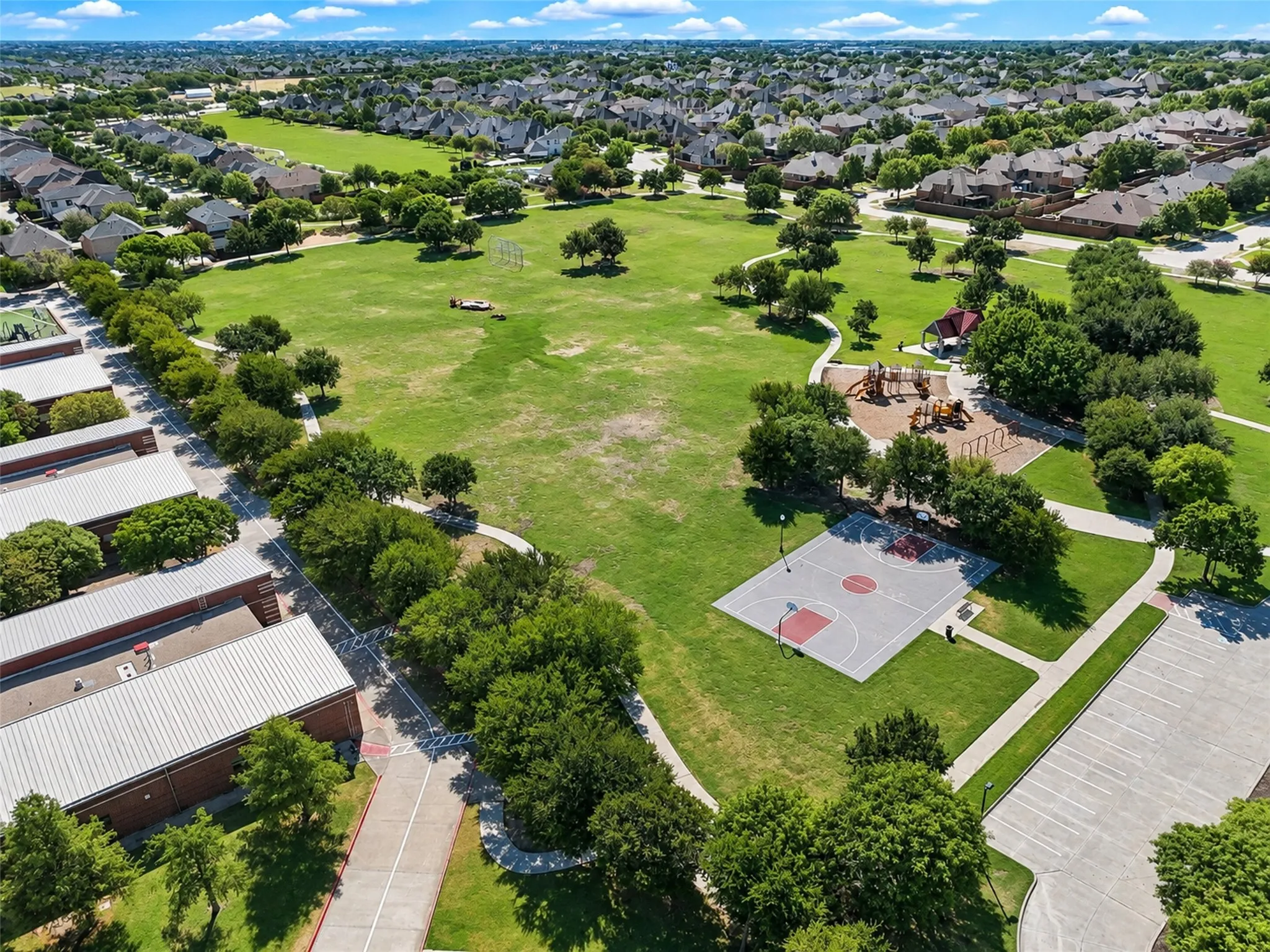 Expansive green space featuring mature trees, a dedicated children's play area, and a basketball court