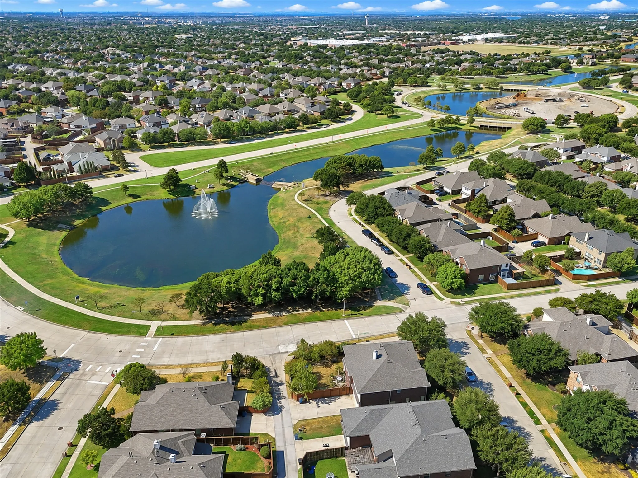 Aerial community overview featuring residential properties, multiple water features, and expansive green spaces