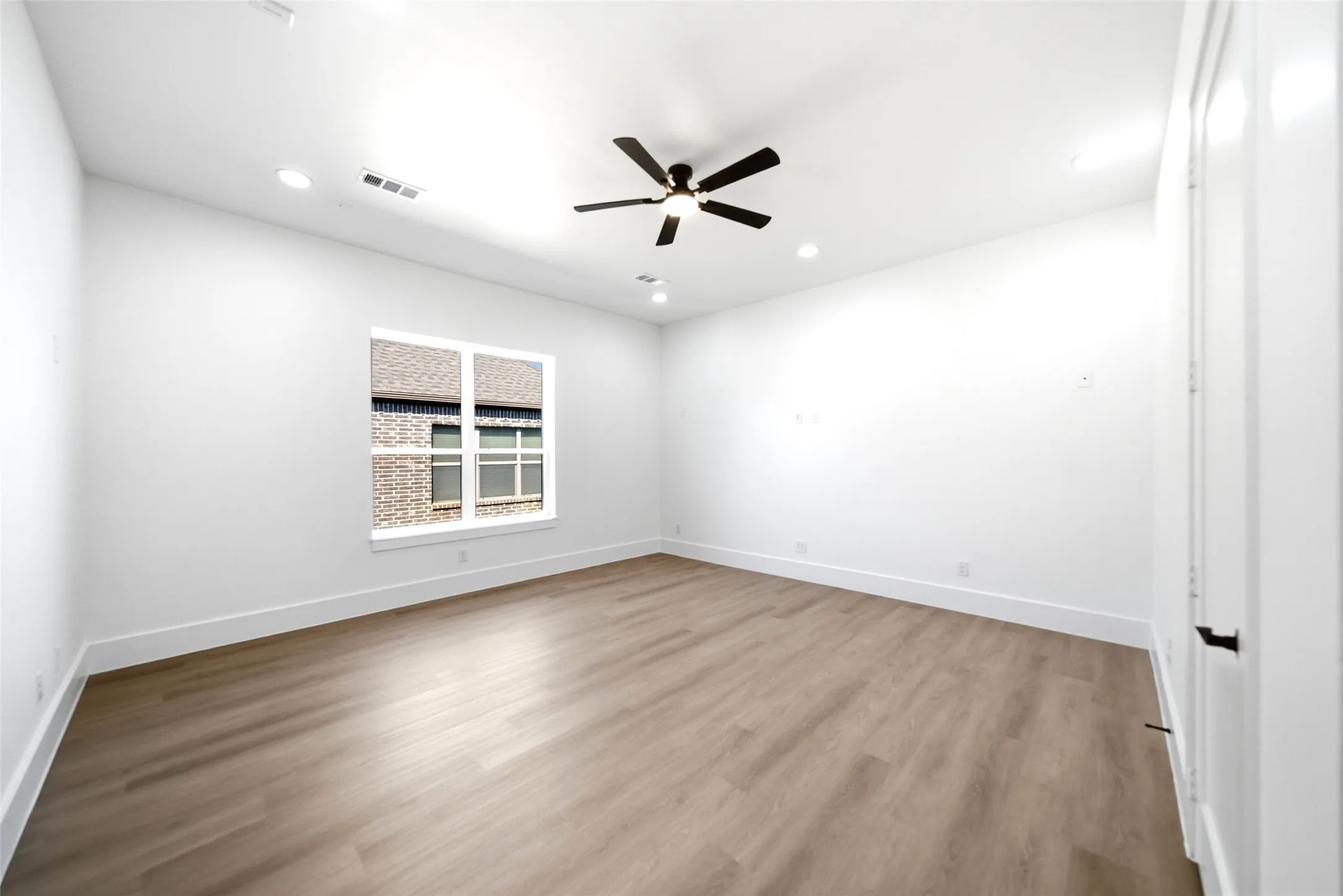 Spacious room featuring wood-finish flooring, a ceiling fan, recessed lighting, and a white-framed window