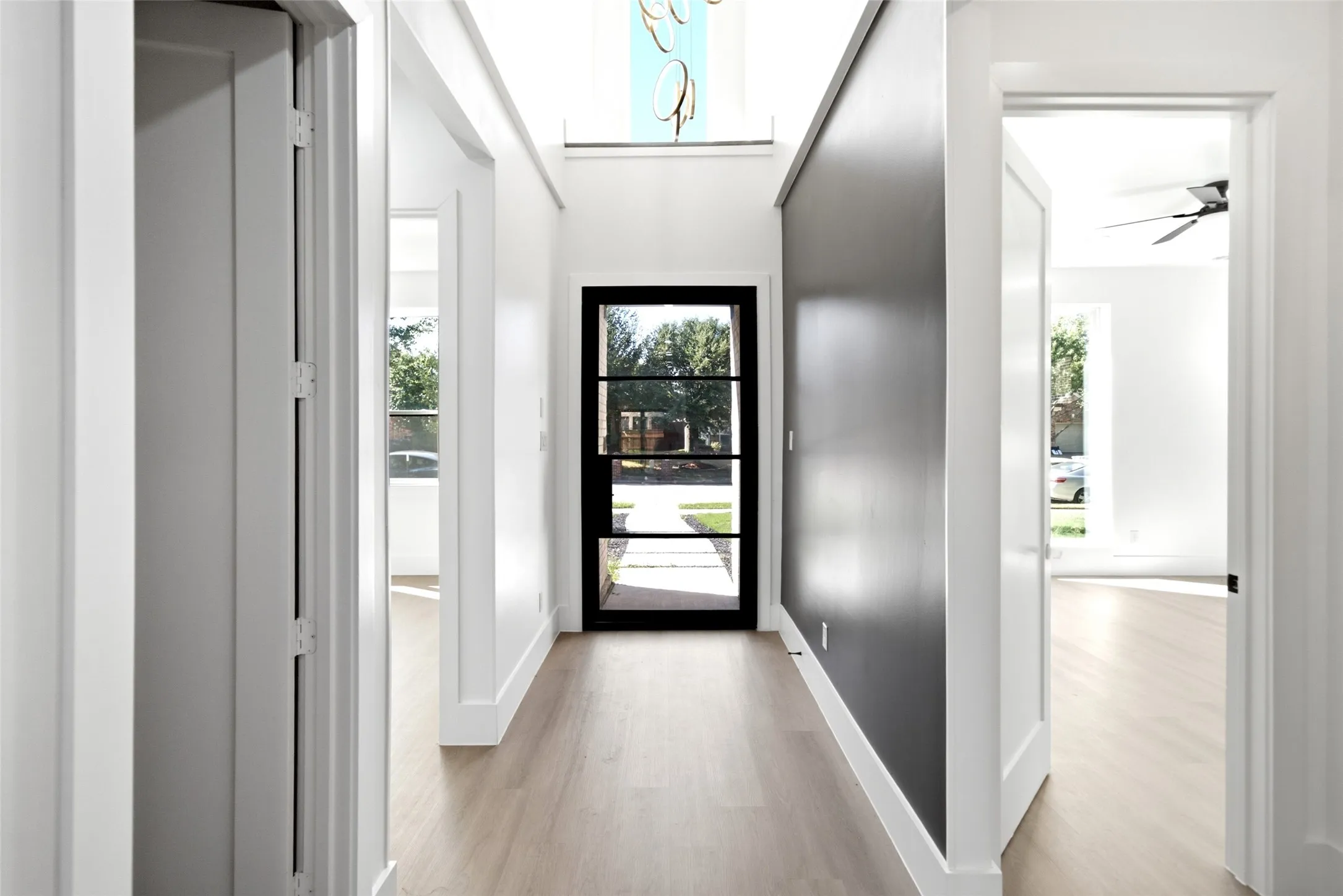 Wood-finish flooring, dark accent wall, a black-framed glass entry door, and white trim throughout