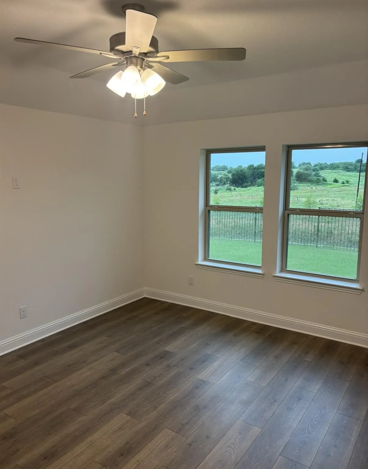 Wood-finish flooring, white walls, and a ceiling fan with integrated lighting
