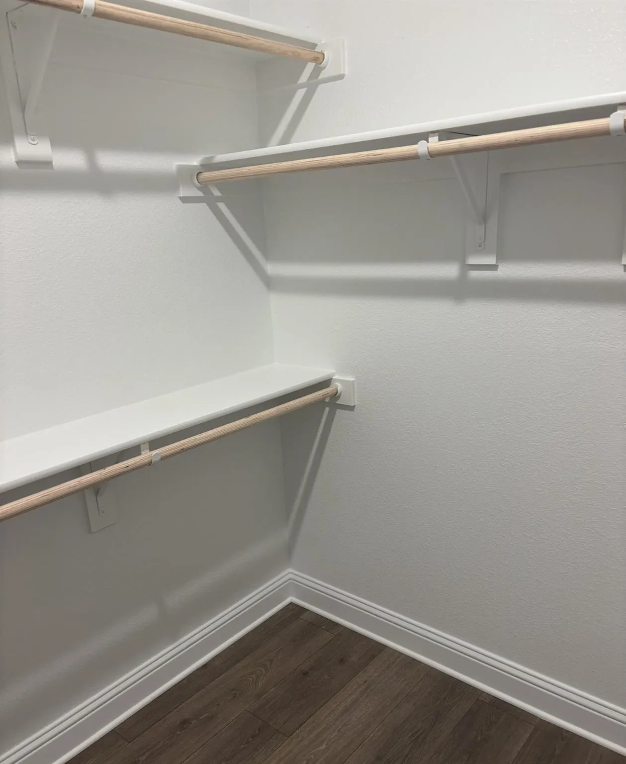 Built-in shelving with hanging rods and wood-finish flooring