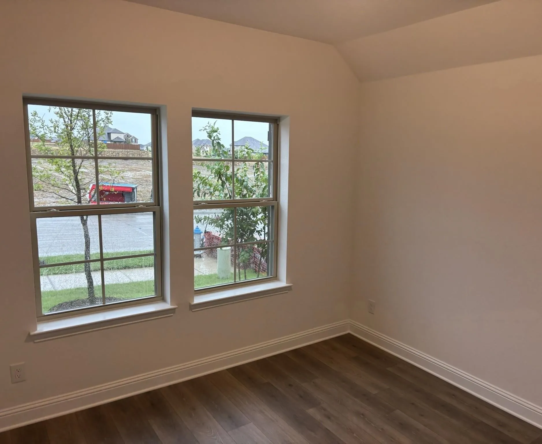 Wood-finish flooring, white walls, and a vaulted ceiling
