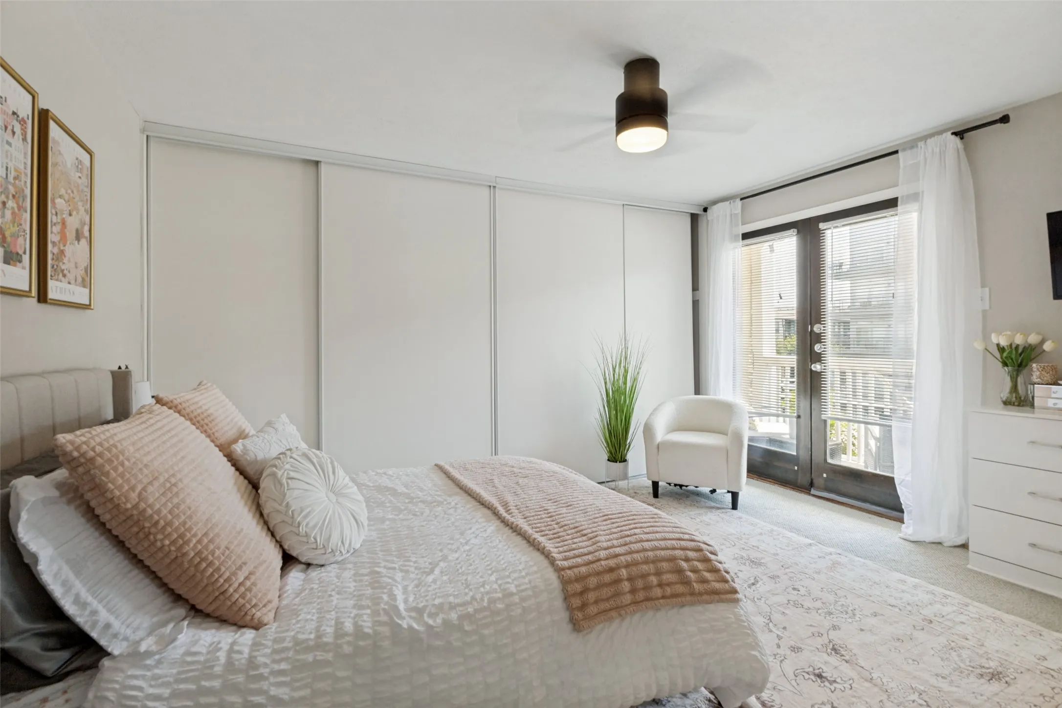 Full-height sliding closet doors, ceiling fan with integrated lighting, wood-finish French doors, and light-colored carpeting