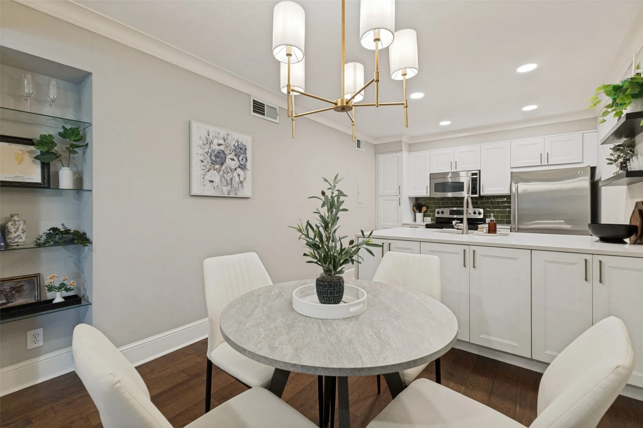 Kitchen featuring white cabinetry, stainless steel appliances, dark green subway tile backsplash, and light countertops