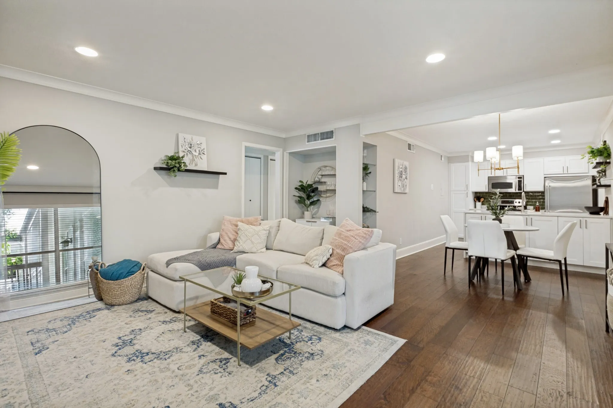 Recessed lighting, wood-finish flooring, built-in shelving, white cabinetry, and stainless steel appliances