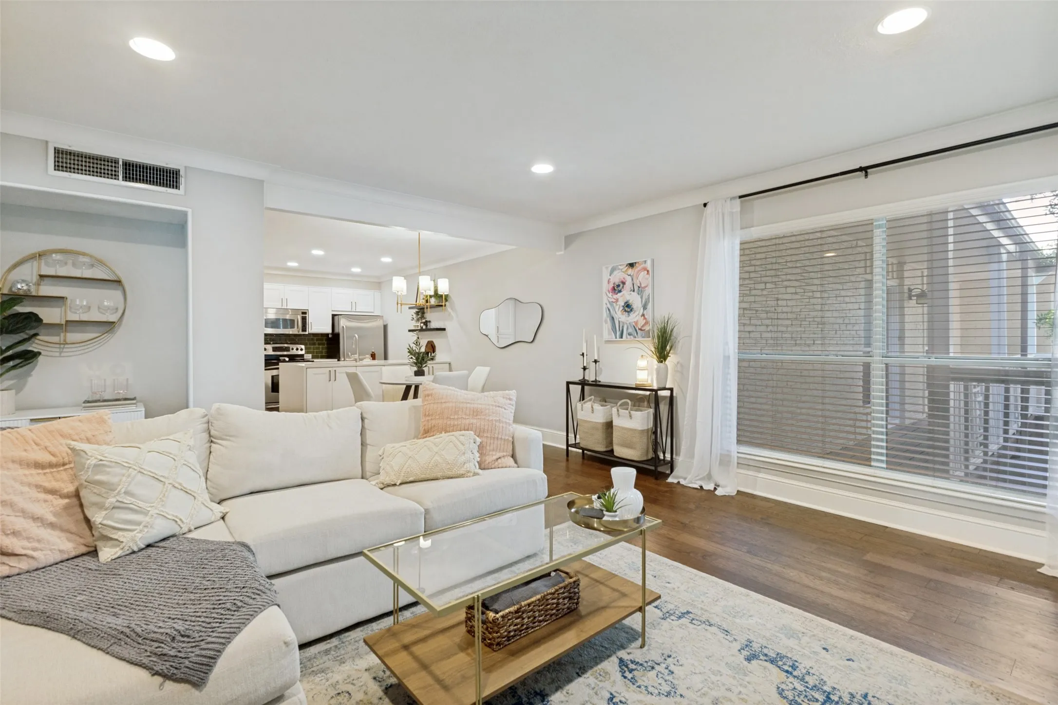 Recessed lighting, wood-finish flooring, large window with blinds, open-concept living area, and white shaker-style cabinetry