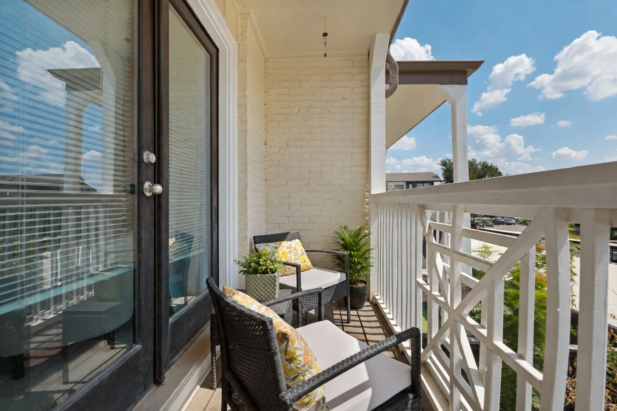 Private balcony with a painted brick exterior, white balusters, and a decorative railing panel