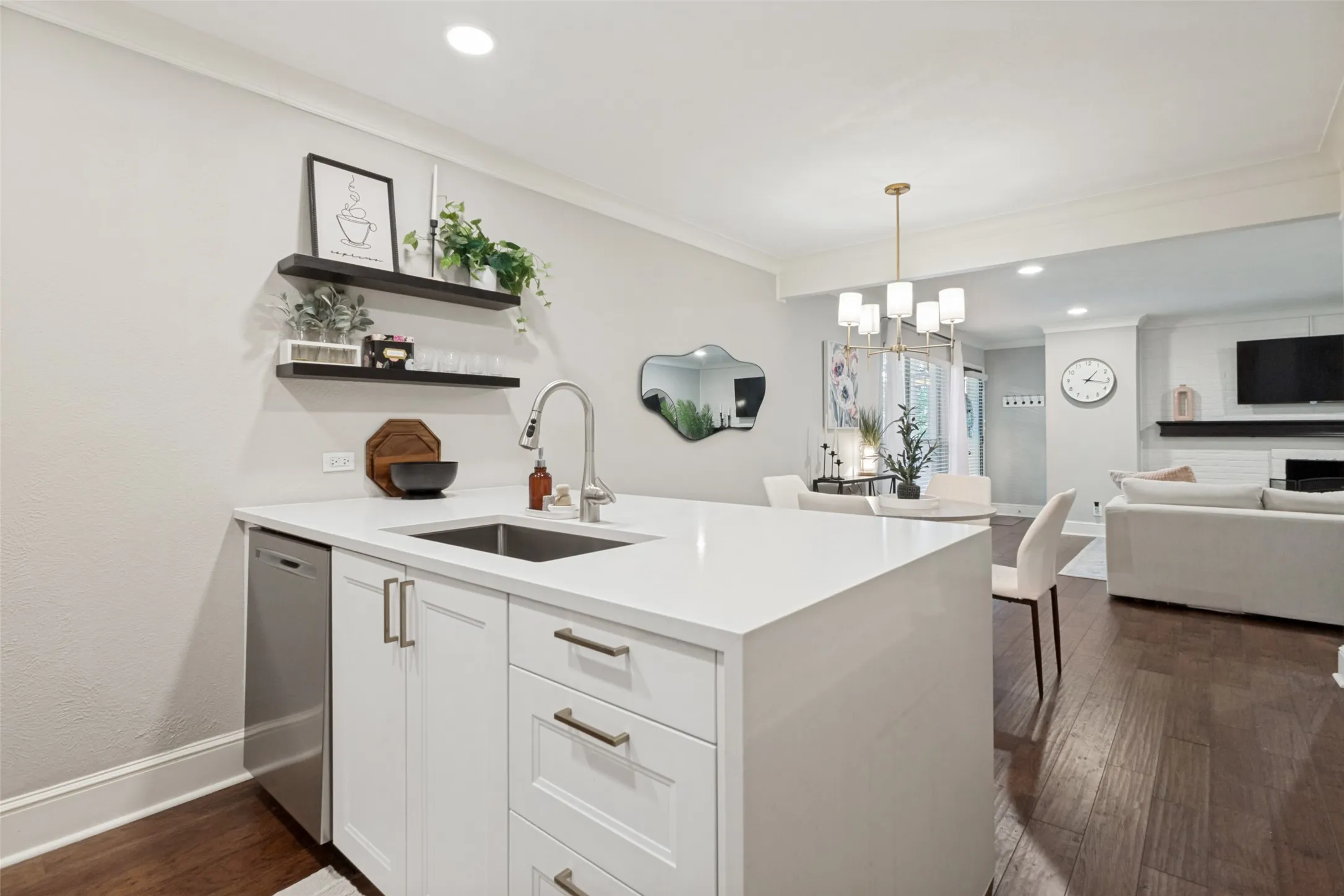 Kitchen island with white cabinetry, stainless steel dishwasher, and an undermount sink with a gooseneck faucet