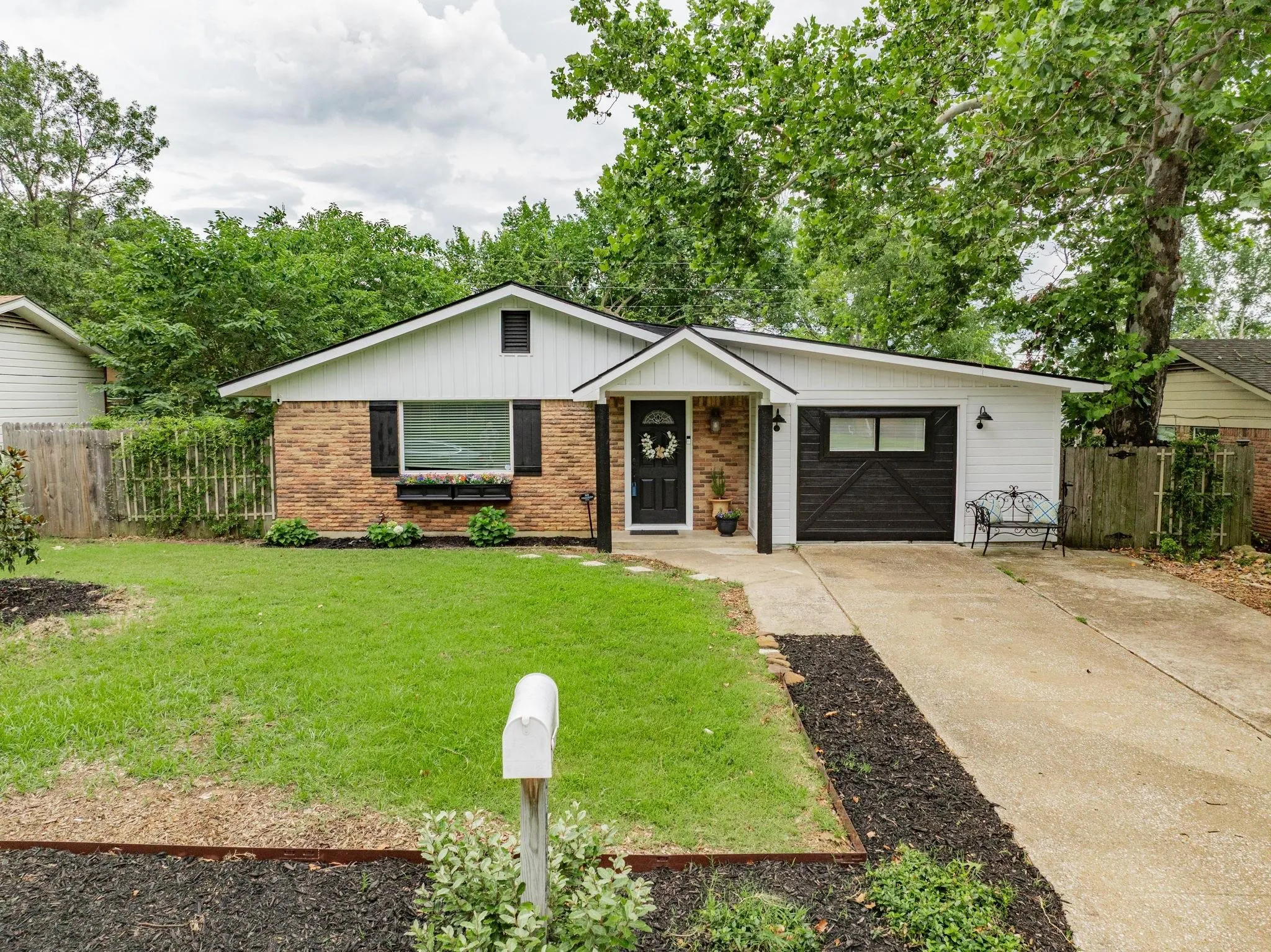 Brick and white siding exterior with a dark wood garage door, a front entry with a dark door, and a concrete driveway
