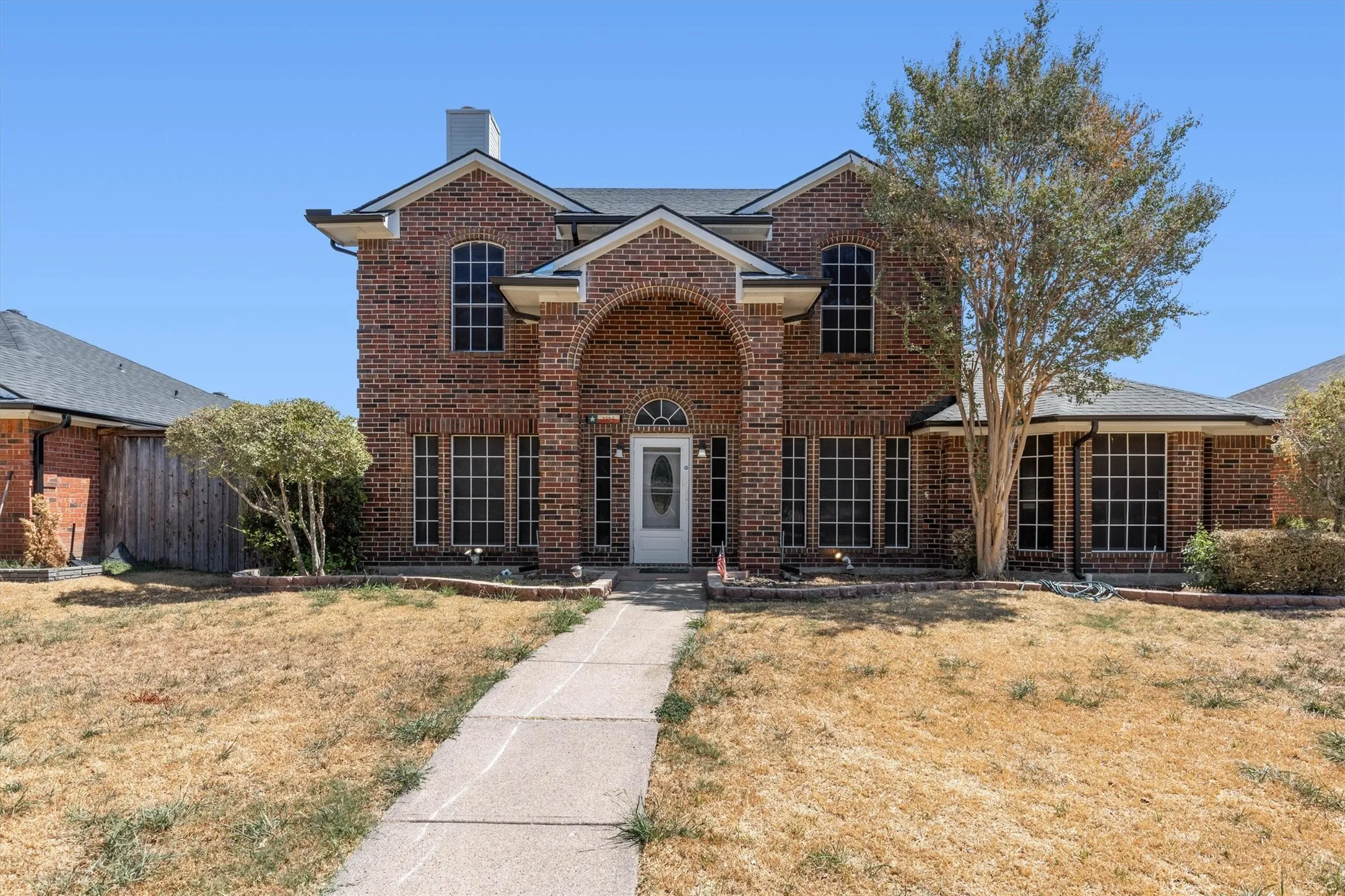 Brick exterior with an arched entryway, multiple grid-pattern windows, and a prominent chimney