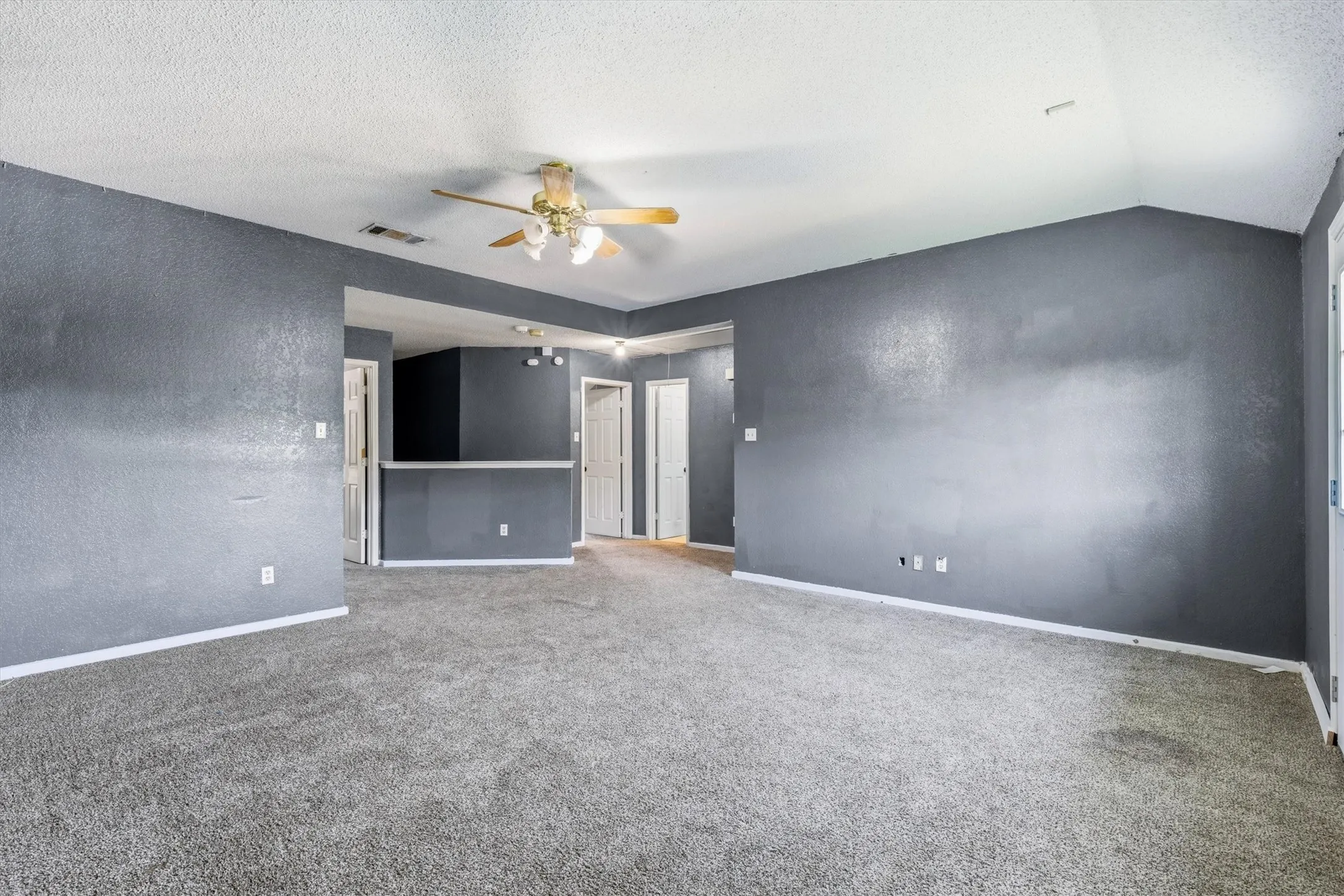Vaulted ceiling with a ceiling fan, gray carpet flooring, and white trim