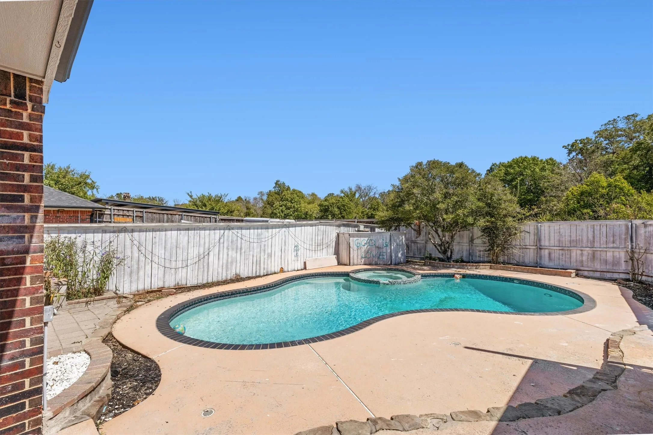 Freeform swimming pool with integrated spa and surrounding concrete patio