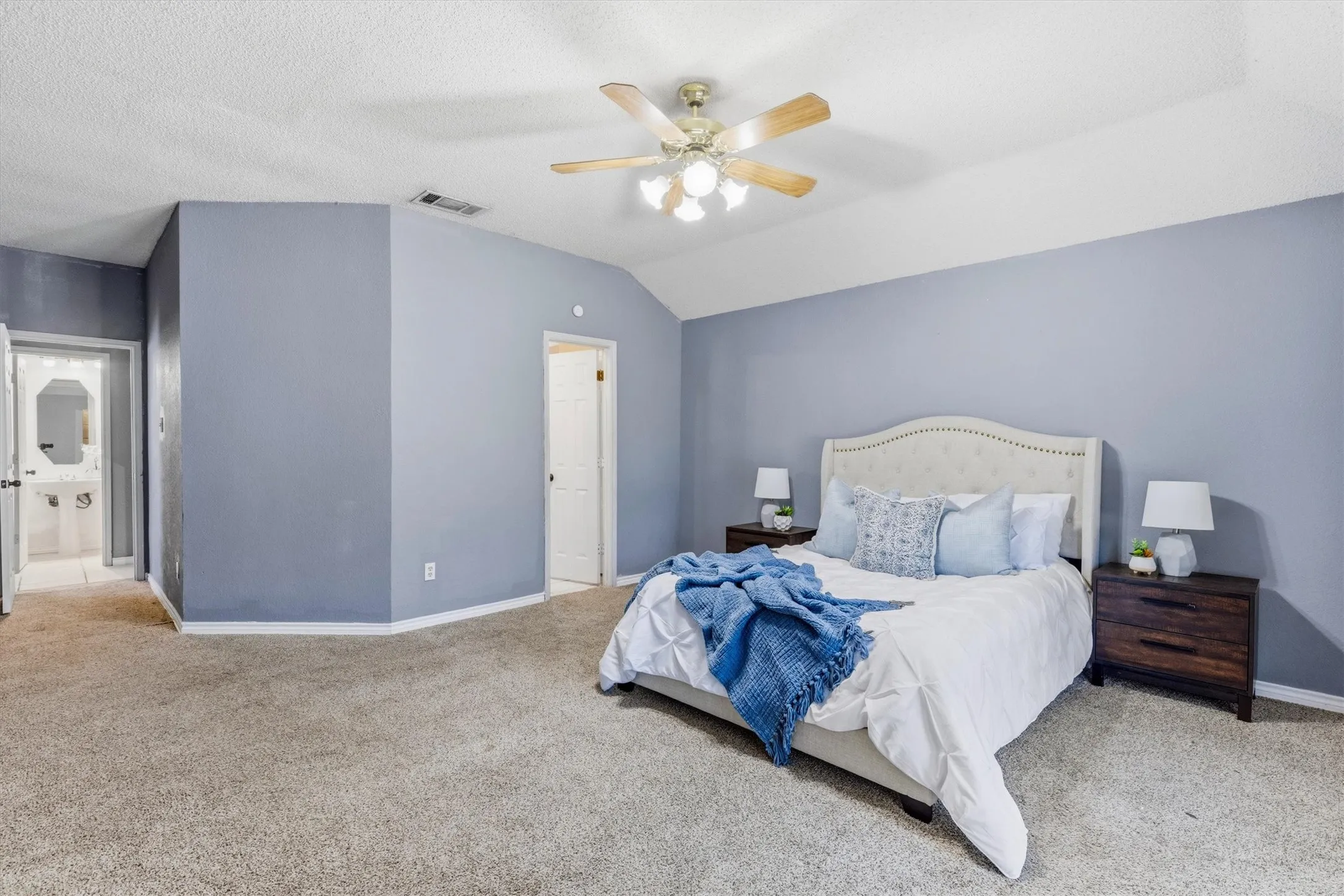Carpeted flooring with a ceiling fan, sloped ceiling, and multiple doorways