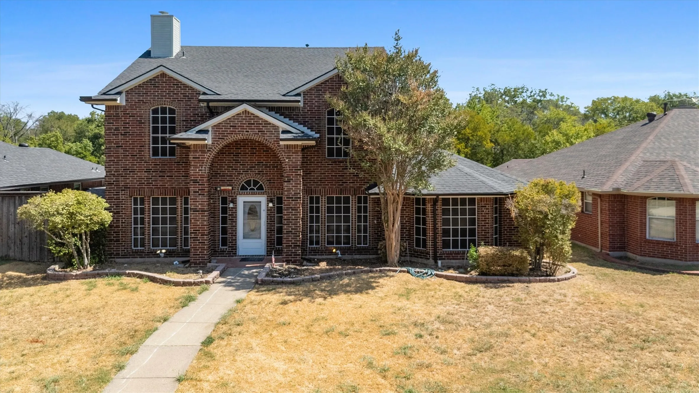 Brick exterior architecture with arched entry, gabled roofline, and multiple window arrays