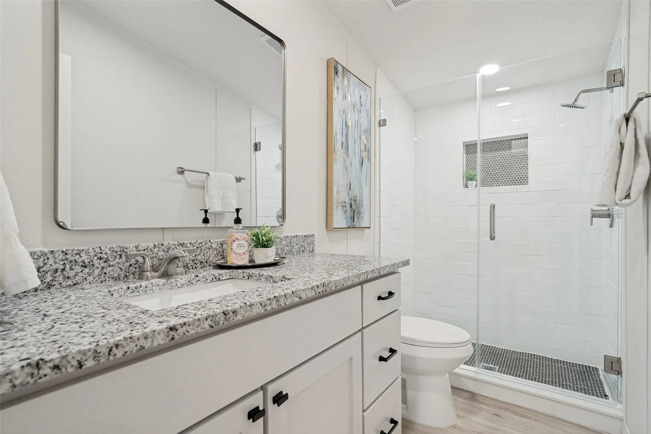 White vanity with stone-finish countertop, undermount sink, and black hardware