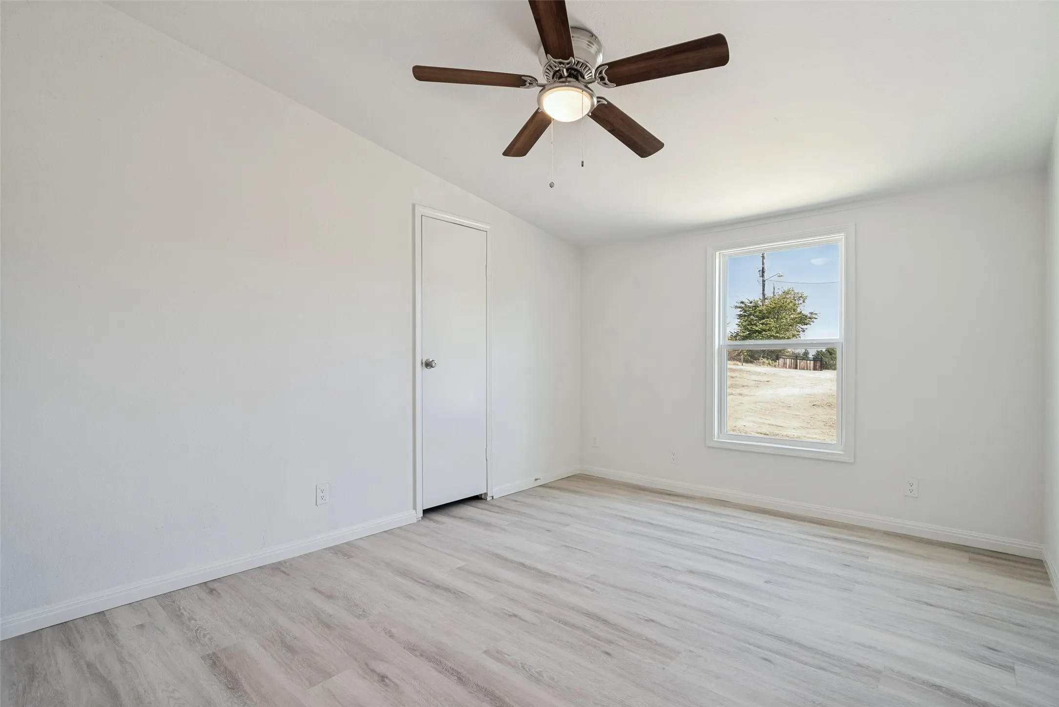 Recessed window with white trim, a ceiling fan with wood-finish blades, light-toned wood-finish flooring, and a white interior door
