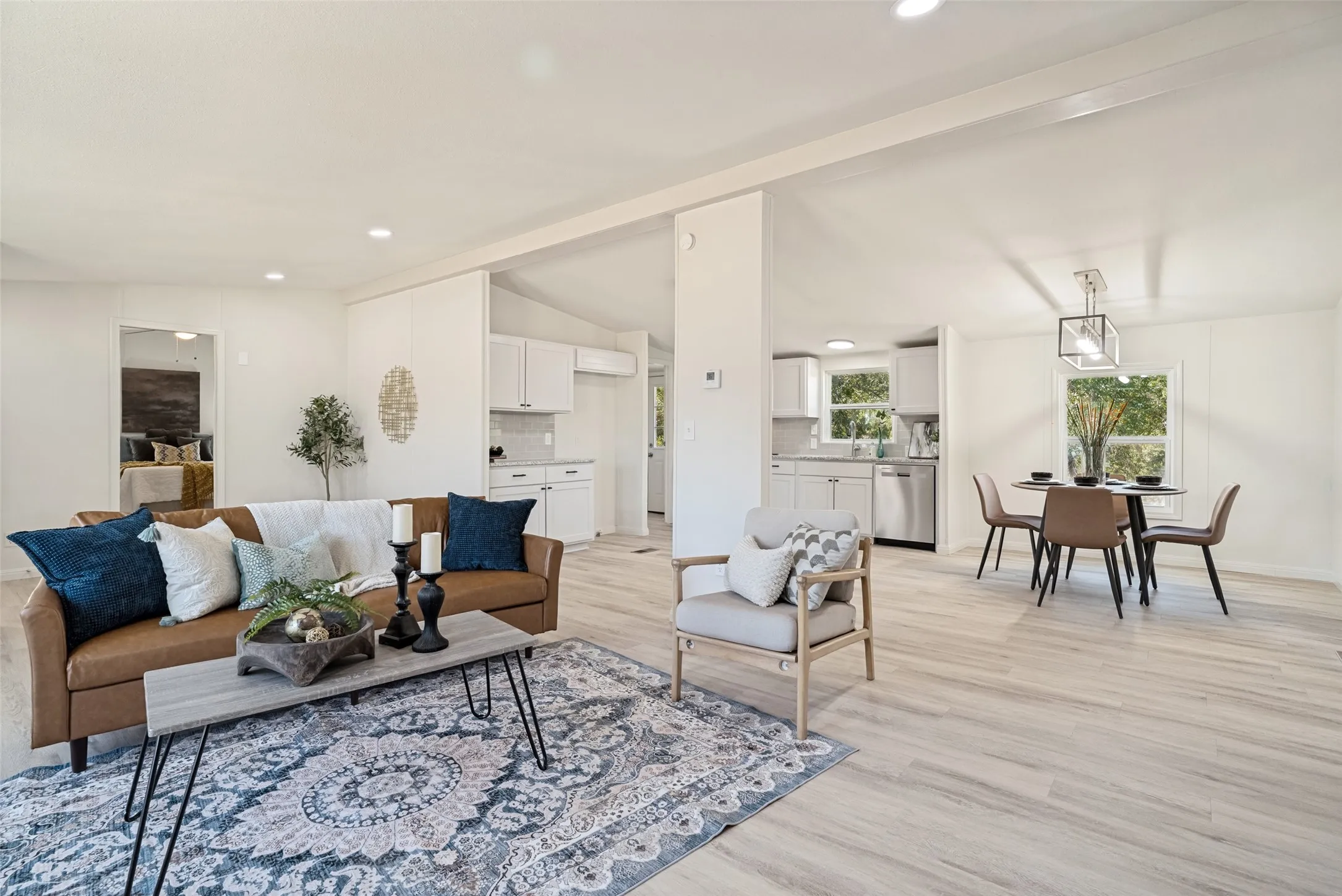 Light wood-finish flooring throughout, recessed ceiling lighting, and a kitchen featuring white cabinetry