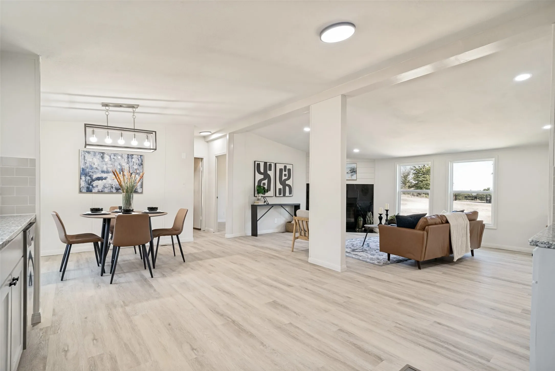 Open-concept living space with light wood-finish flooring, white walls, and recessed lighting