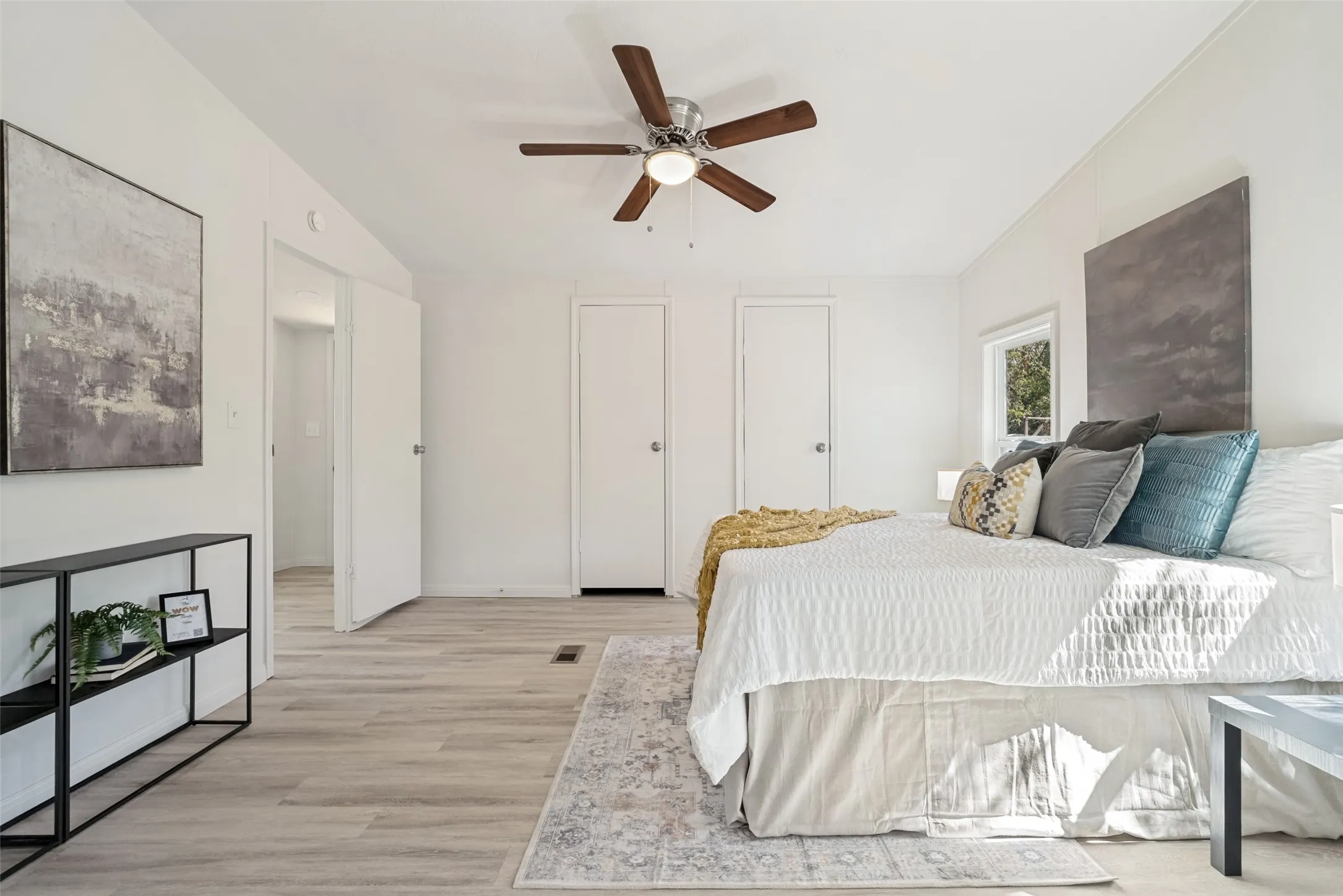 Light wood-finish flooring, white walls, and a ceiling fan with wood-tone blades
