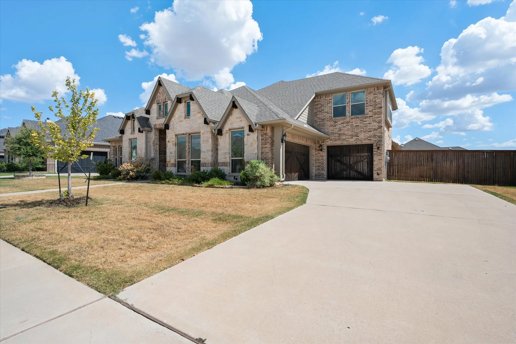 Here's your driveway and garage — plenty of space to park, with that same beautiful stone and brick carrying all the way across the front elevation.