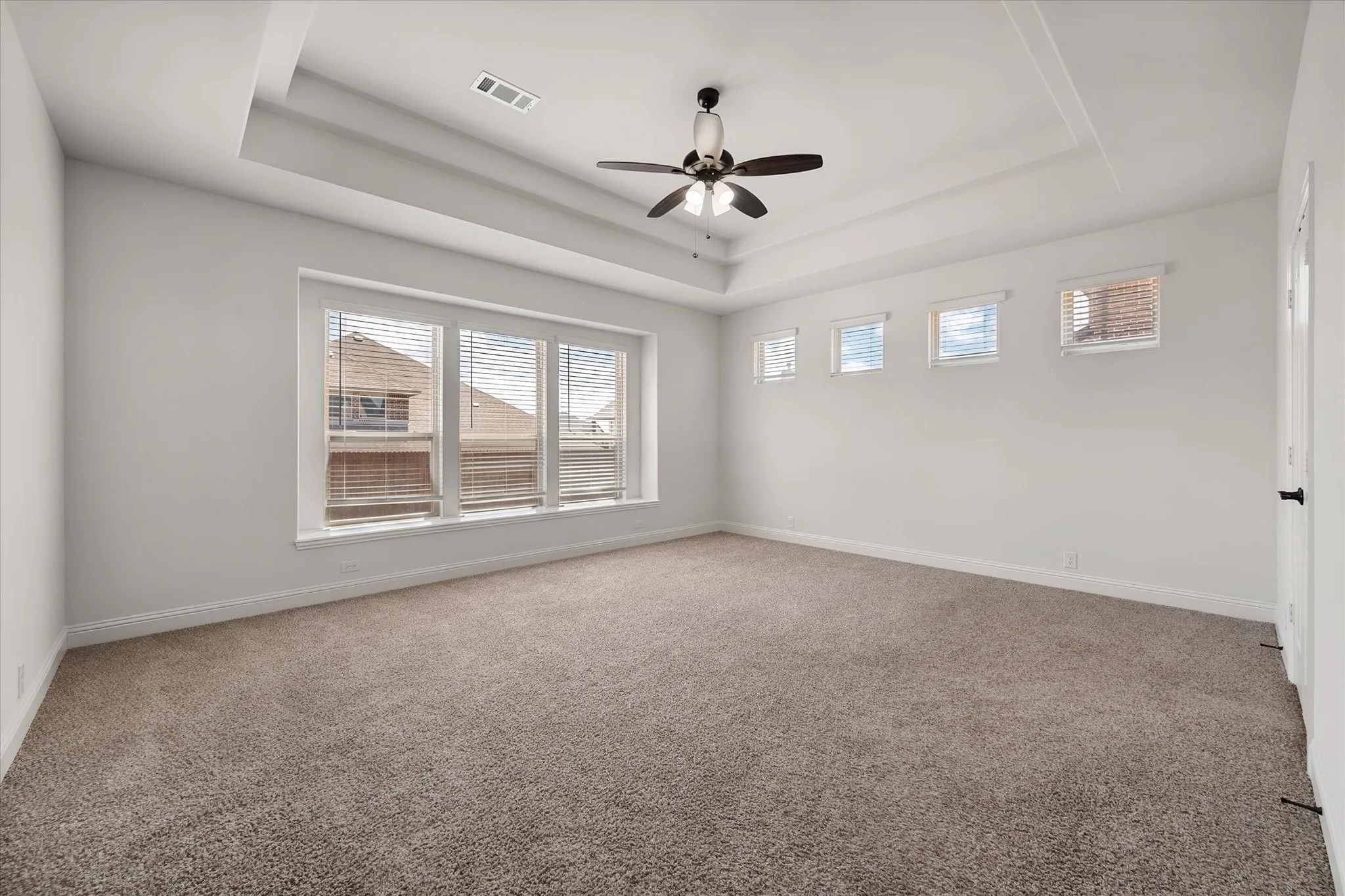 Okay, now for the primary suite — just look at the tray ceiling and row of windows up top. It's such a peaceful, well-lit retreat.